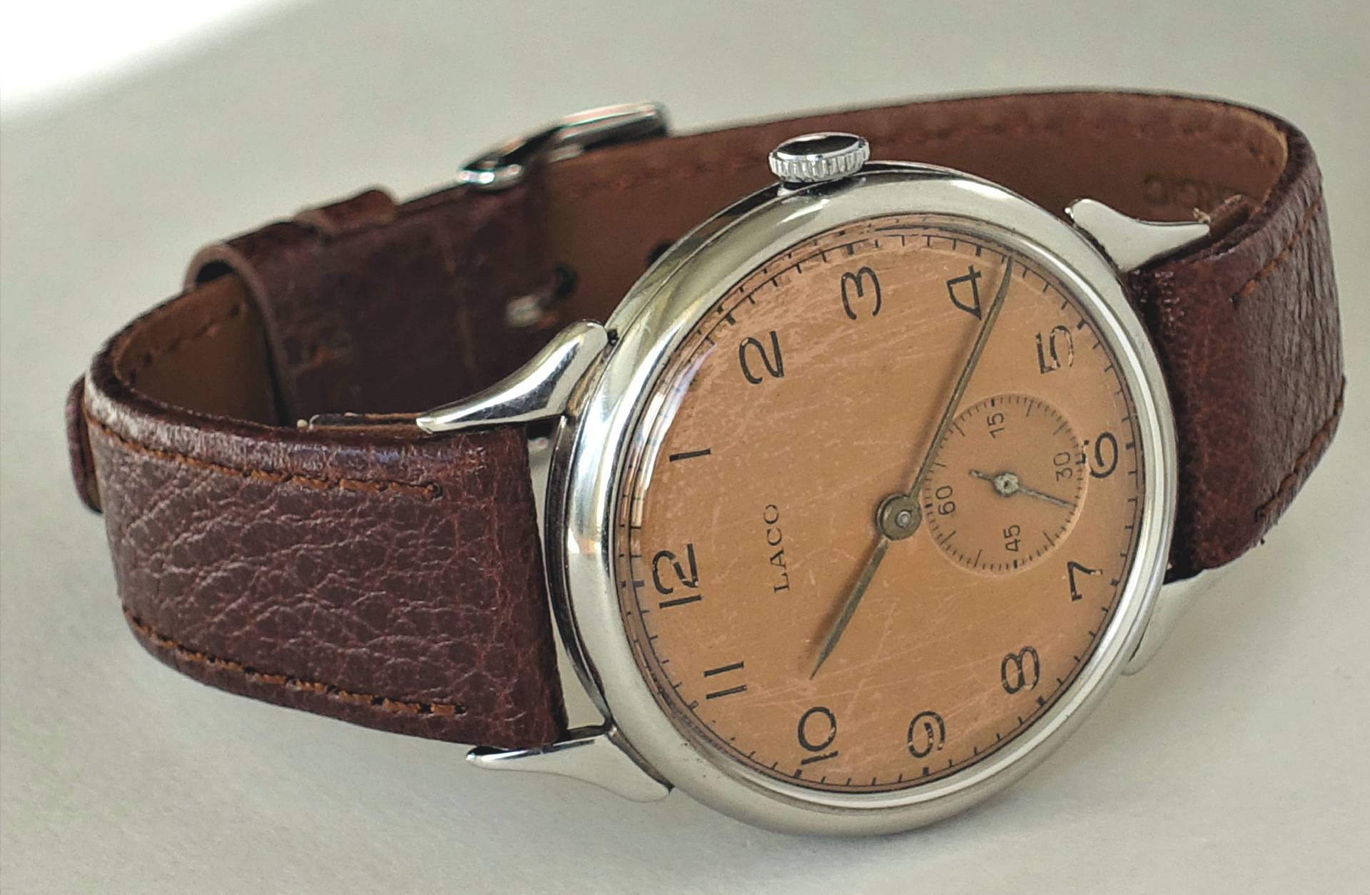 Armbanduhr mit braunem Lederarmband und beigem Zifferblatt, silberfarbenes Gehäuse.