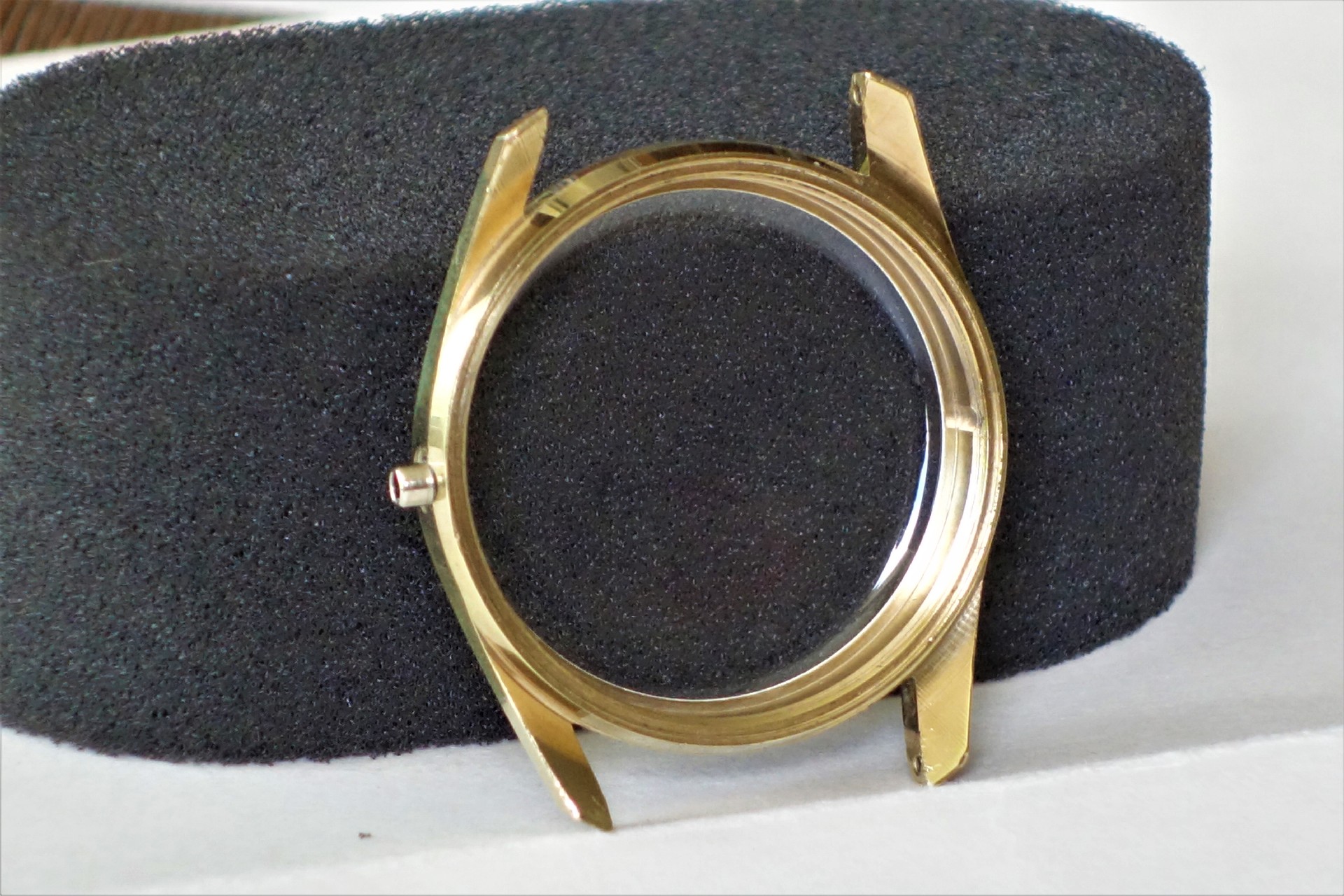 Rundes Uhrengehäuse aus goldfarbenem Metall mit Glasabdeckung.