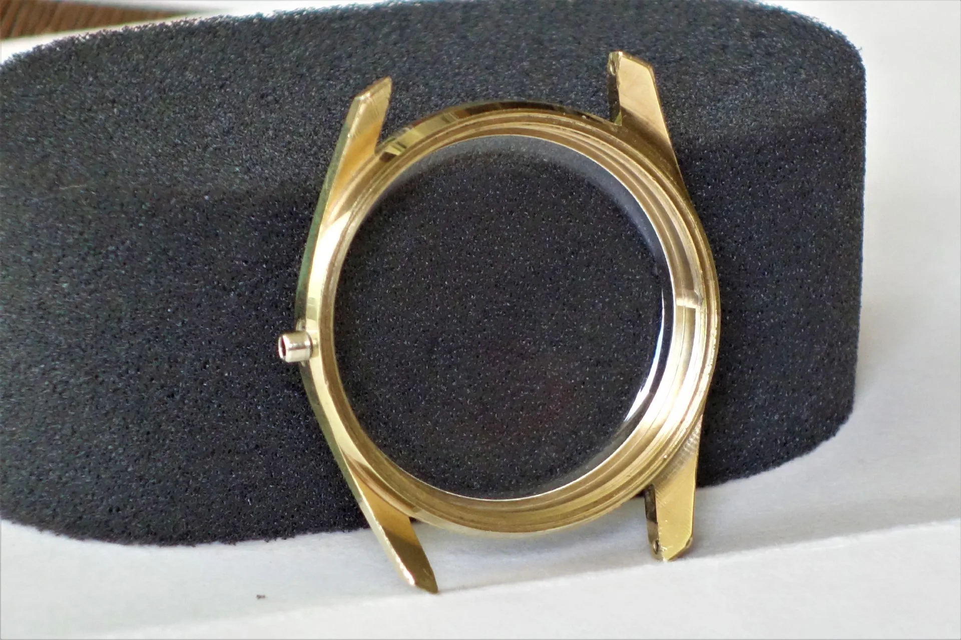 Rundes Uhrengehäuse aus goldfarbenem Metall mit Glasabdeckung.