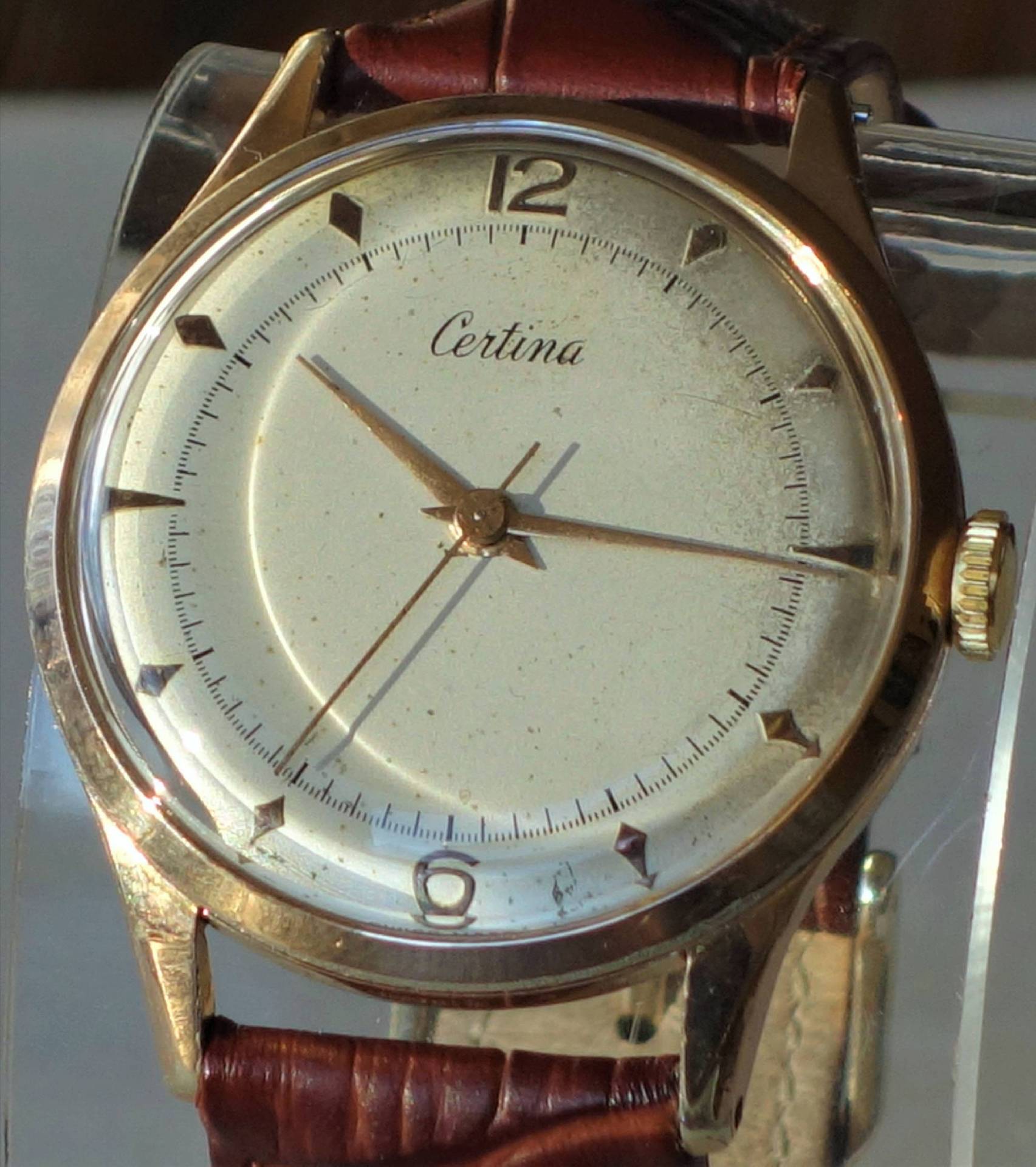 Goldfarbene Certina Armbanduhr mit hellem Zifferblatt und braunem Armband.