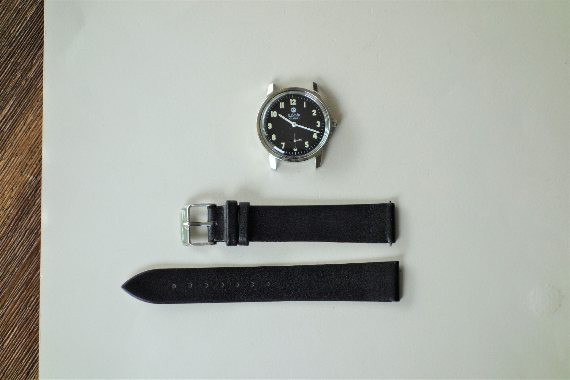 Zweiteiliges schwarzes Uhrenarmband mit silberfarbener Dornschließe.