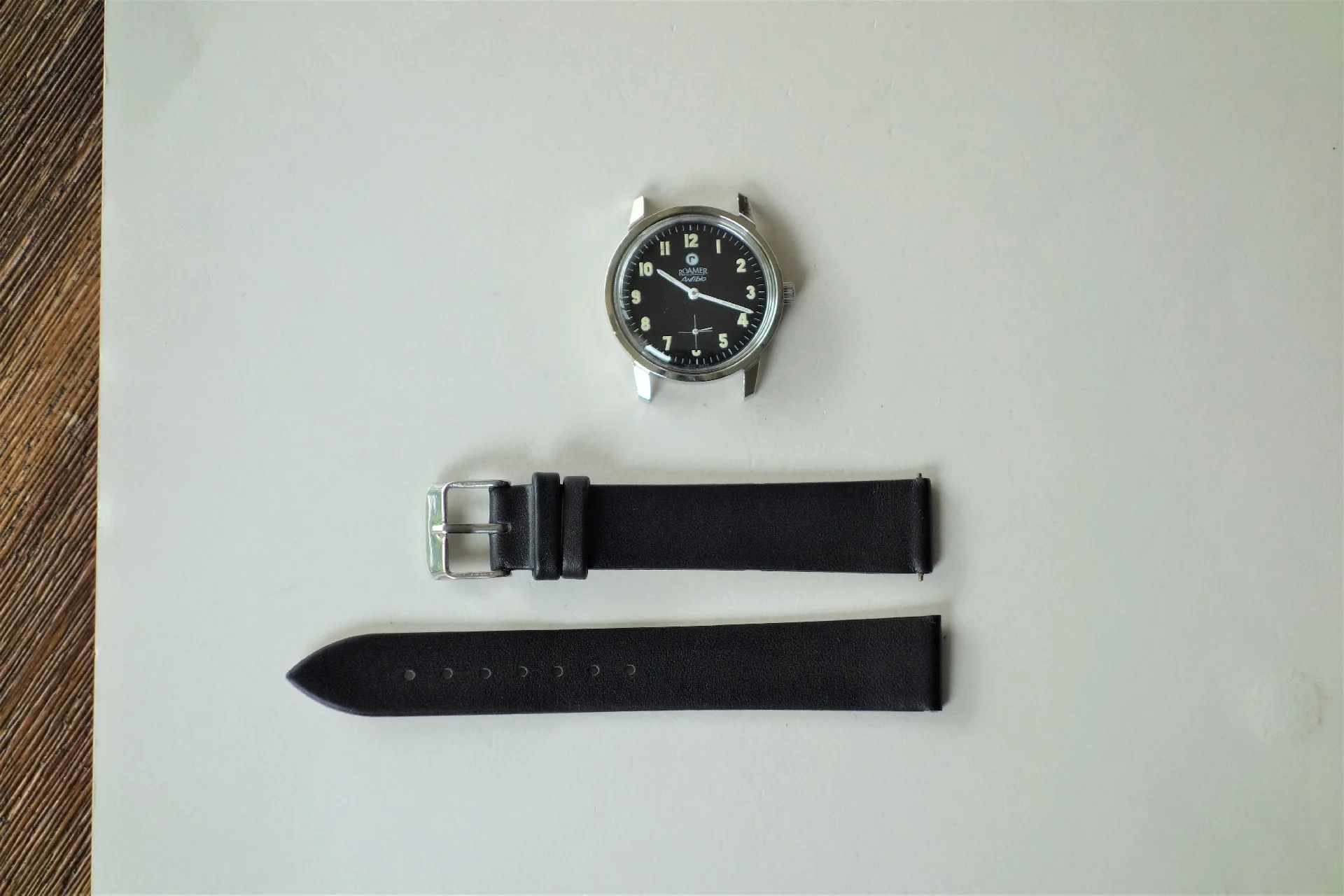 Zweiteiliges schwarzes Uhrenarmband mit silberfarbener Dornschließe.