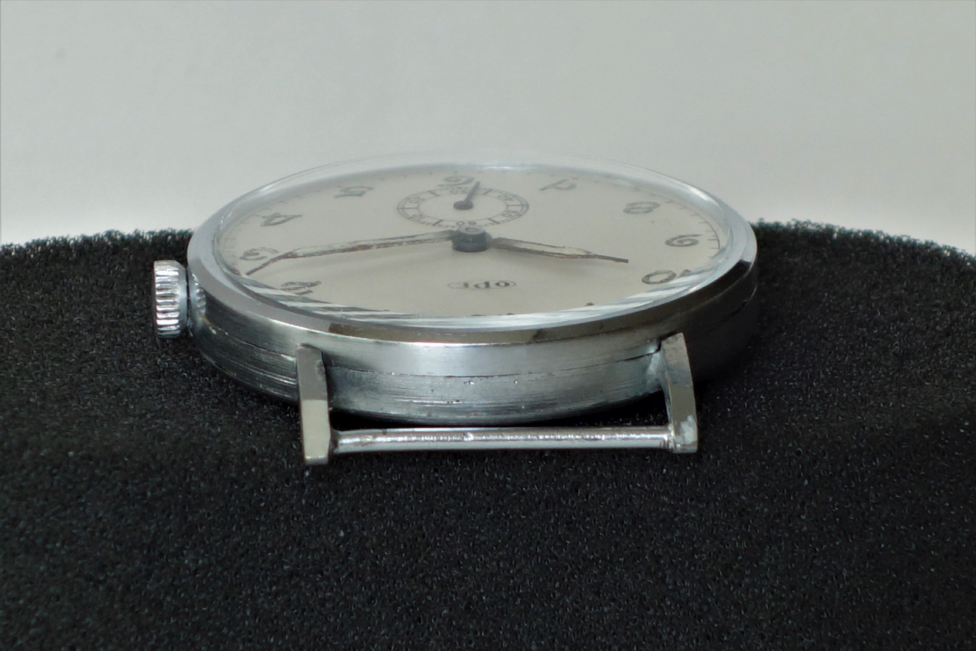 Flache mechanische Armbanduhr mit silberfarbenem Gehäuse und hellem Zifferblatt ohne Armband.