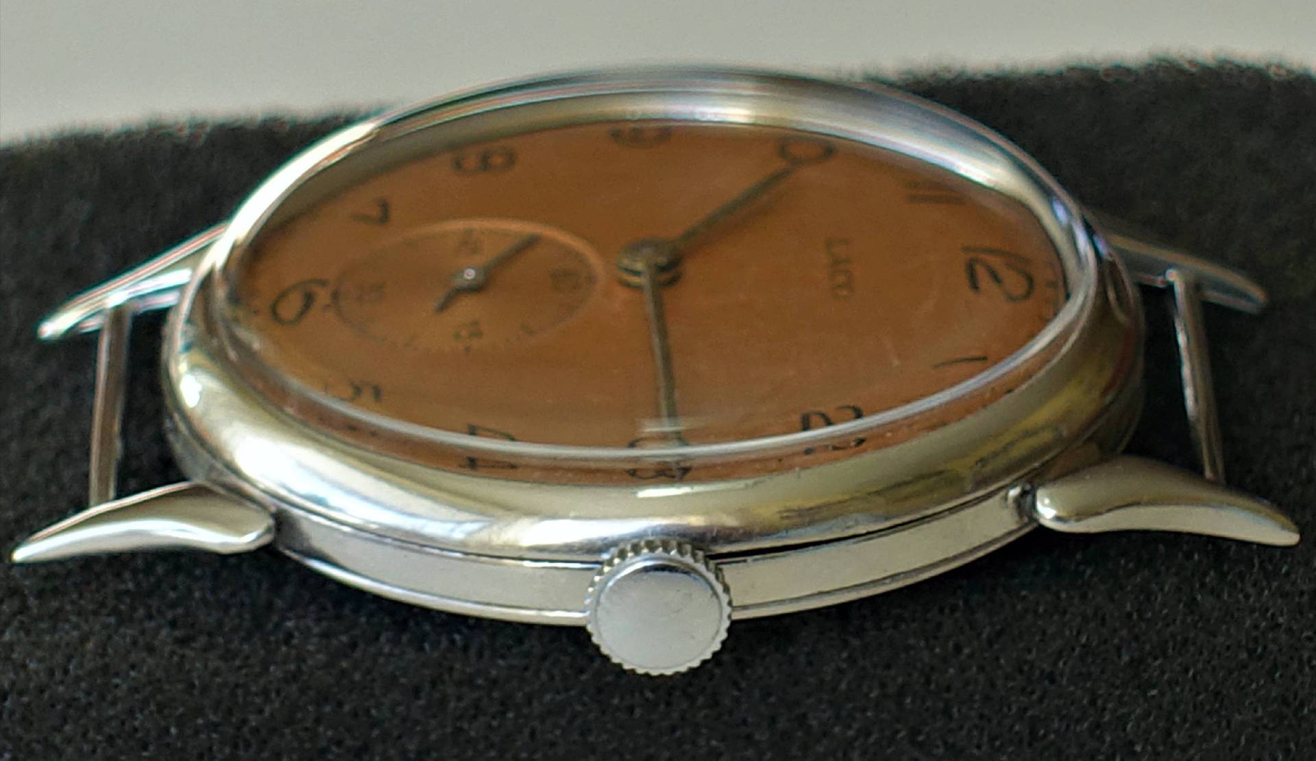 Silberfarbene Armbanduhr mit braunem Zifferblatt und seitlicher Krone.