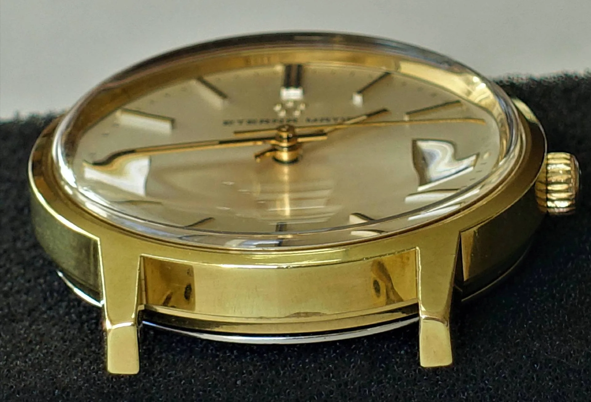 Goldfarbene Armbanduhr mit hellem Zifferblatt und goldenen Zeigern.