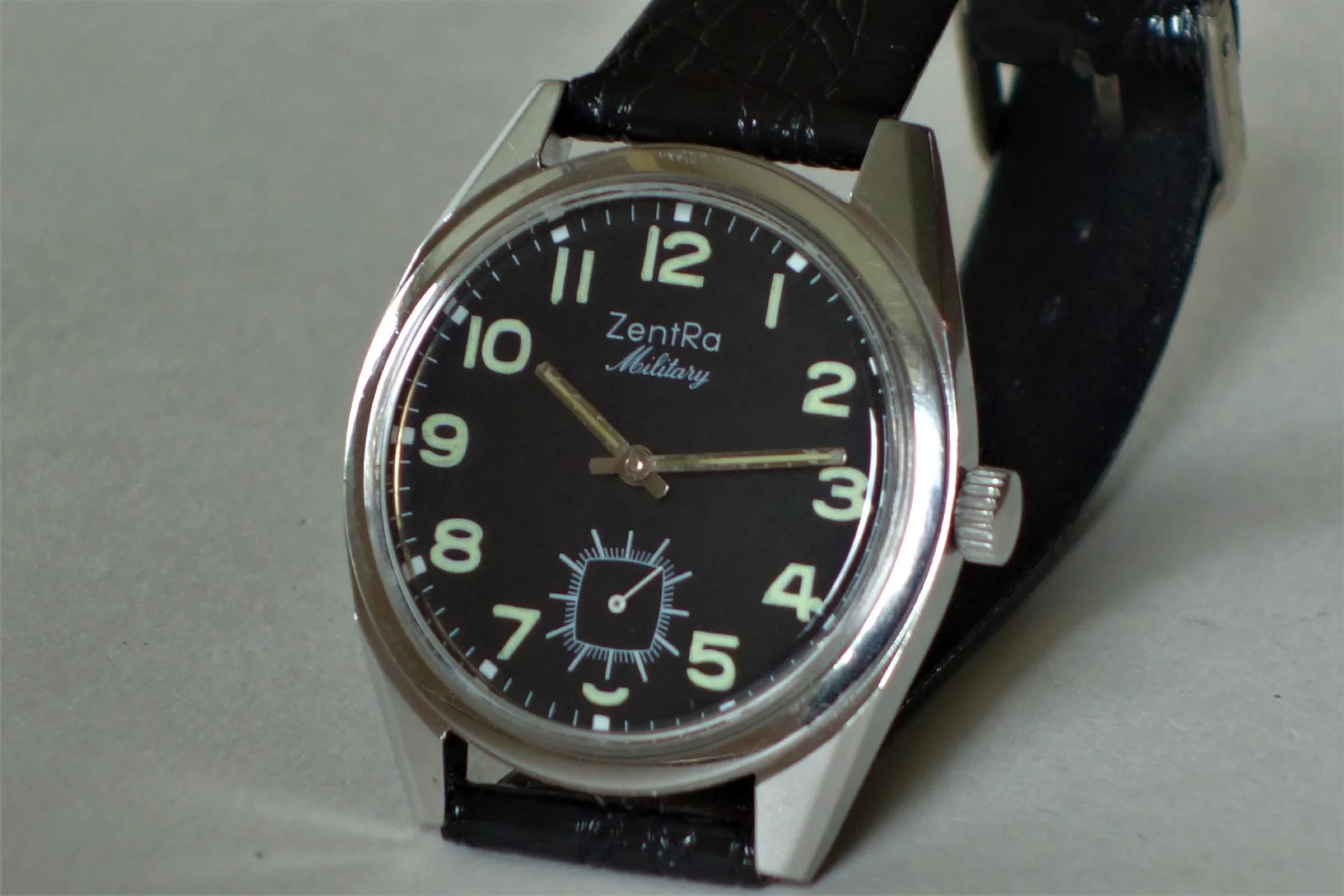 ZentRa Military Uhr Schwarze Armbanduhr mit silberfarbenem Gehäuse und schwarzem Armband, Zifferblatt mit Leuchtzahlen und kleiner Sekunde.