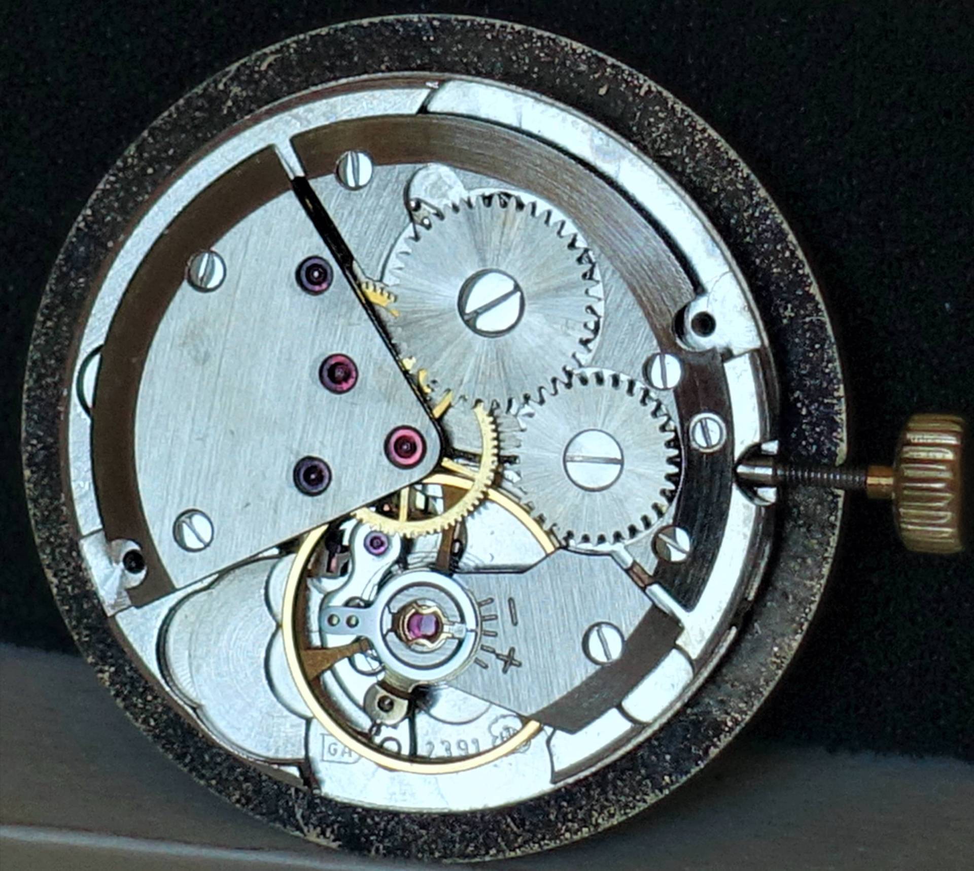 Silberfarbenes mechanisches Uhrwerk mit sichtbaren Zahnrädern und Aufzugskrone.