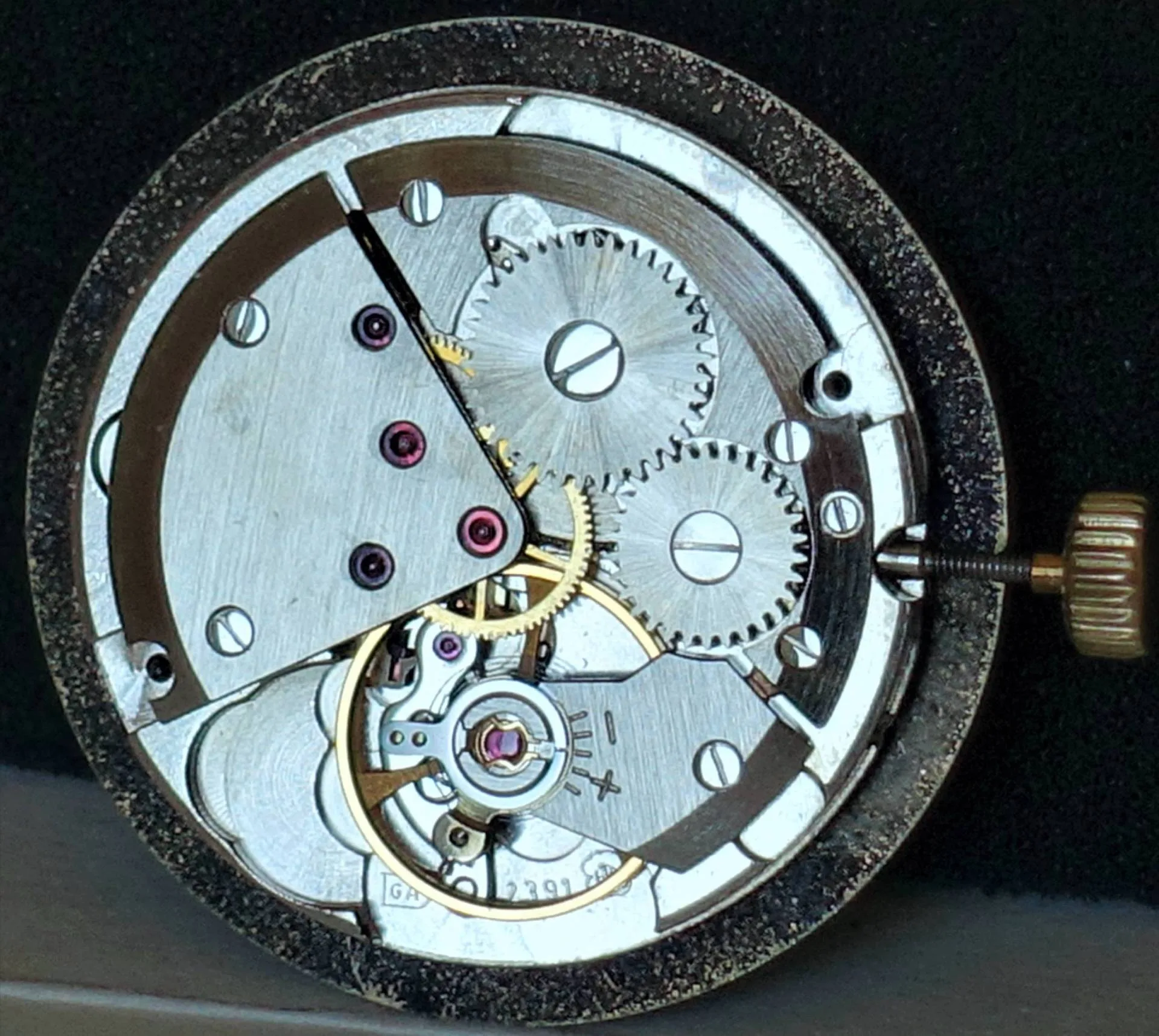 Silberfarbenes mechanisches Uhrwerk mit sichtbaren Zahnrädern und Aufzugskrone.