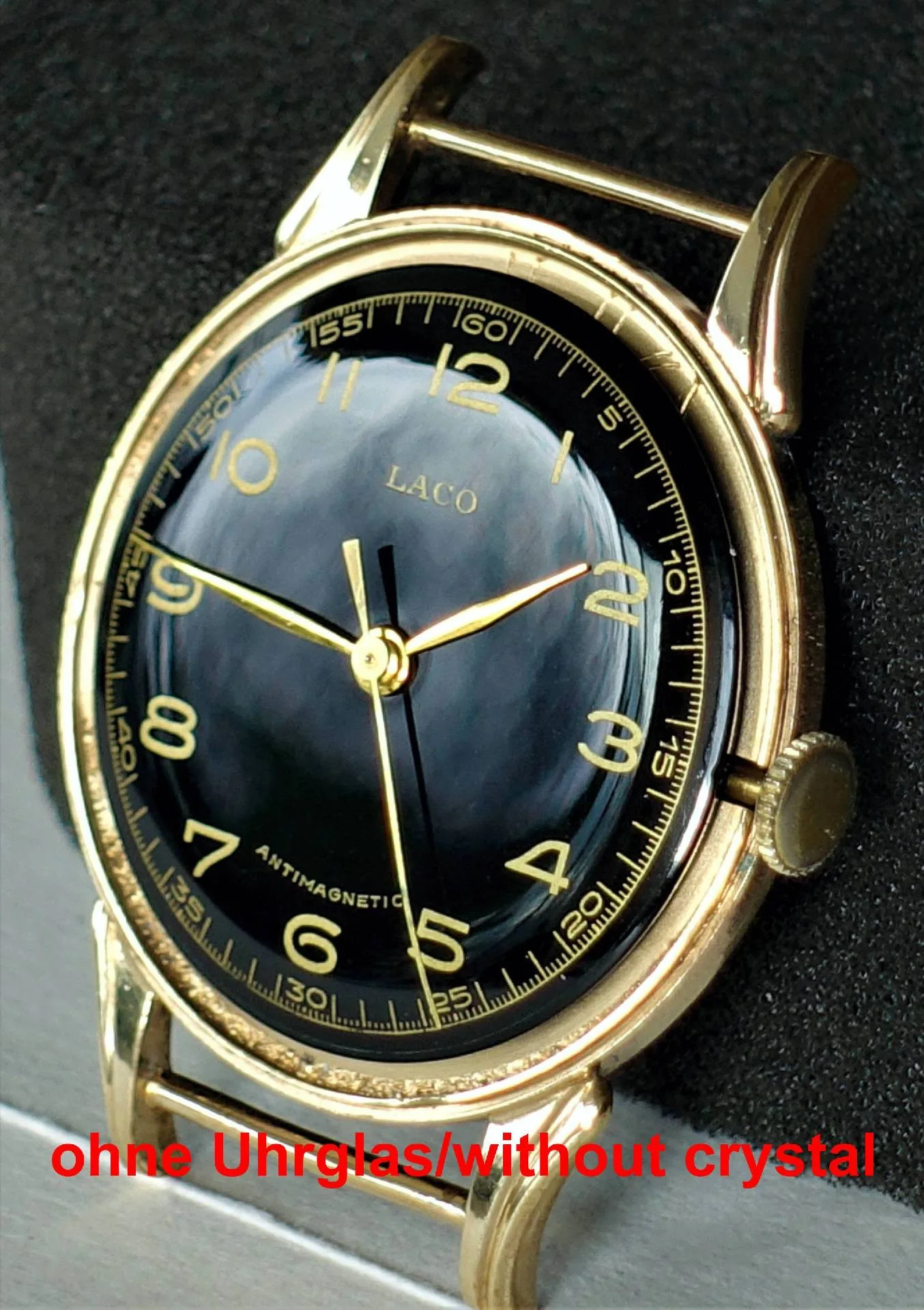 Eine Armbanduhr mit schwarzem Zifferblatt und gelbem Gehäuse, bei der das Uhrglas fehlt.
