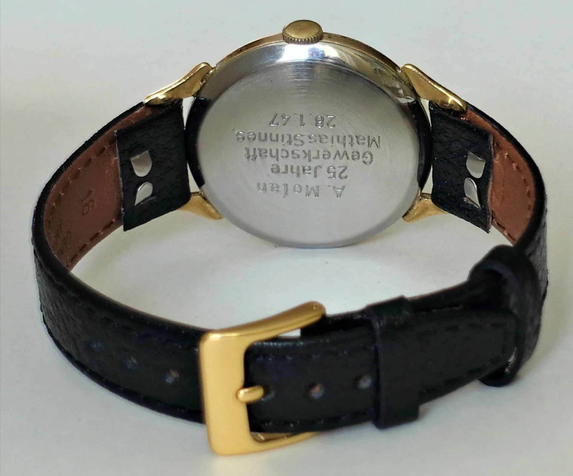 Armbanduhr schwarz goldfarben Schwarze Armbanduhr mit goldfarbenen Elementen und silberfarbener Rückseite.