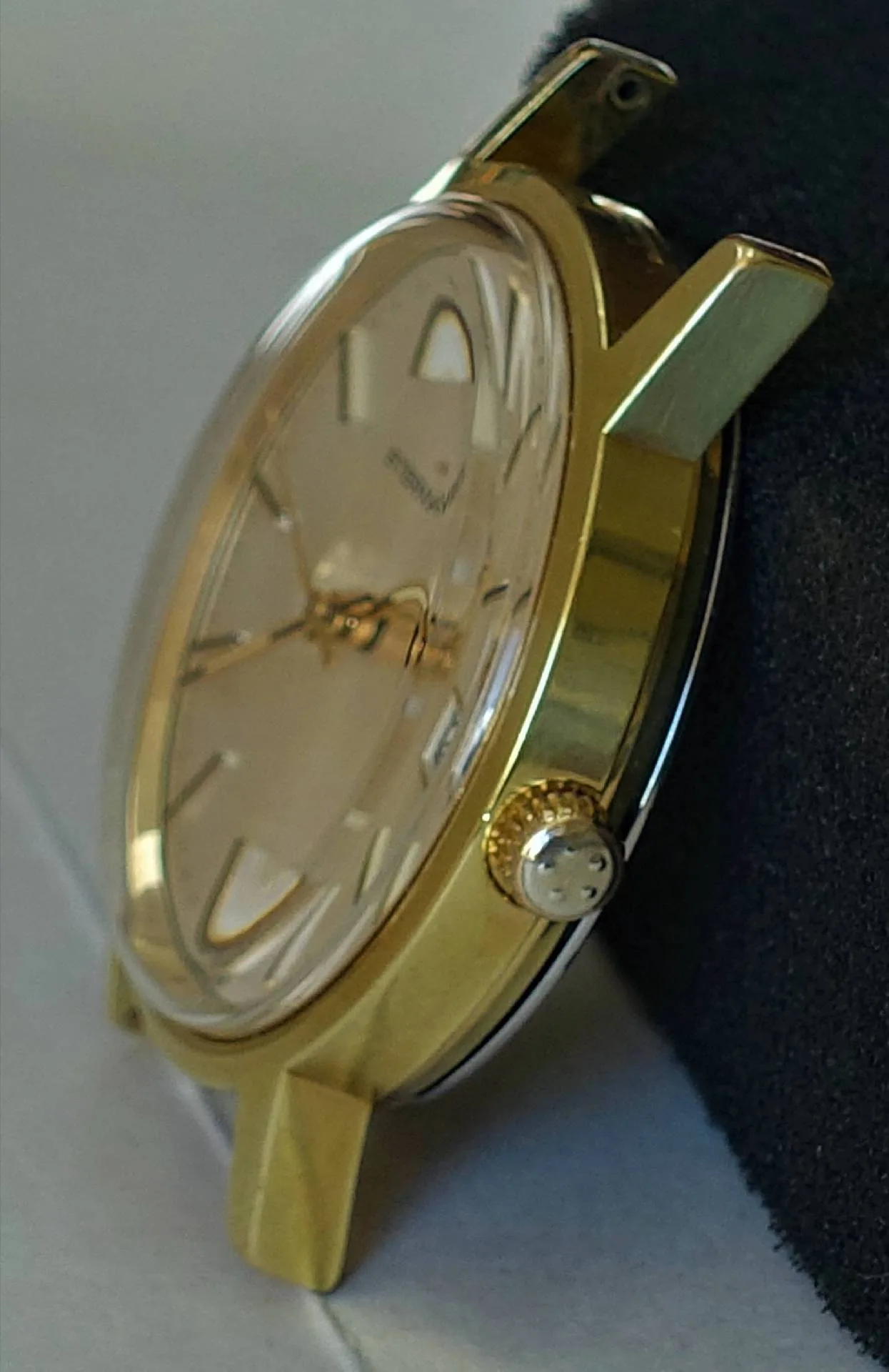 Goldfarbene Armbanduhr mit hellem Zifferblatt und silberner Krone.