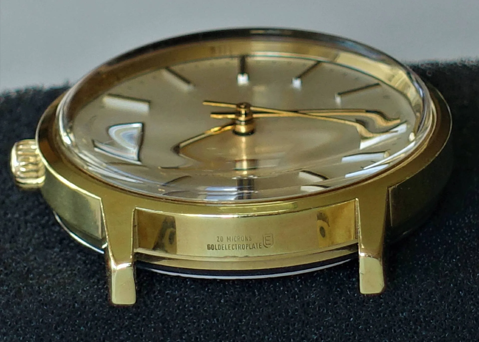 Goldfarbene Armbanduhr mit rundem Gehäuse und goldfarbenem Zifferblatt.
