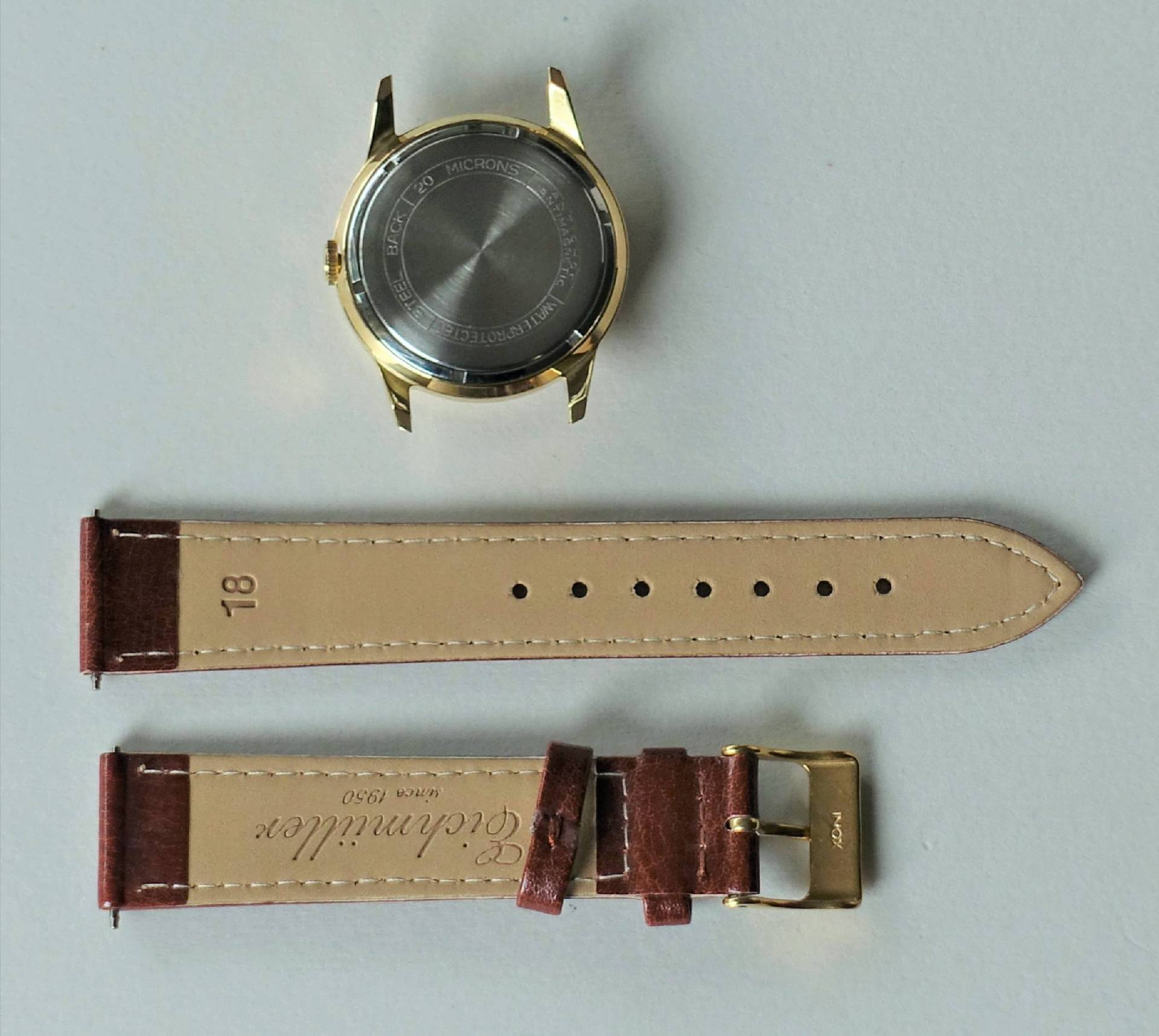 Goldfarbenes Uhrgehäuse mit braunem Lederarmband und goldfarbener Schließe.