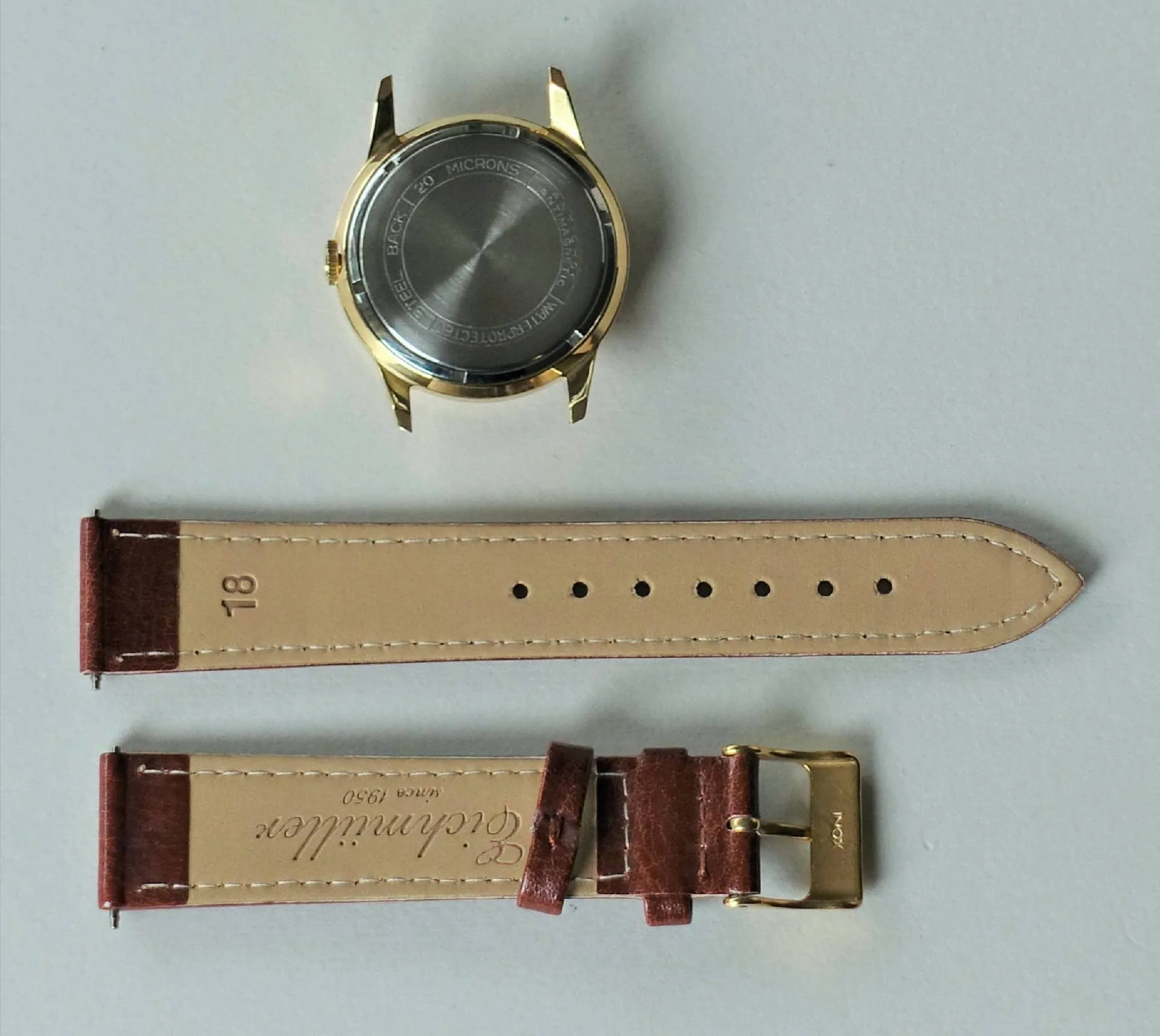 Uhrgehäuse goldfarben mit Lederarmband Goldfarbenes Uhrgehäuse mit braunem Lederarmband und goldfarbener Schließe.