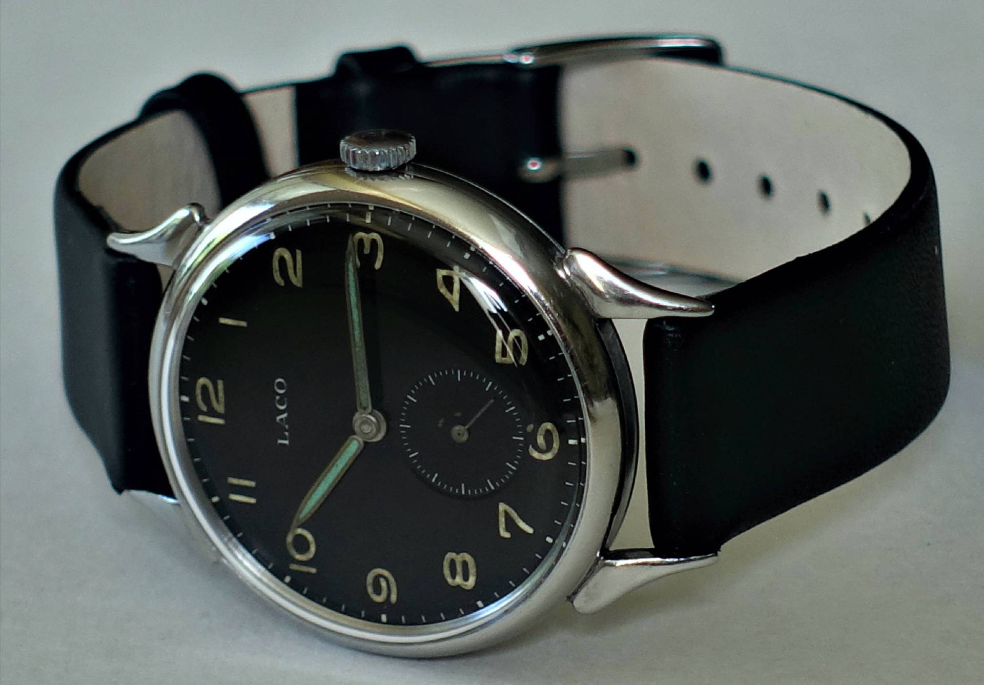 Schwarze Armbanduhr mit silberfarbenem Gehäuse und schwarzem Lederarmband.