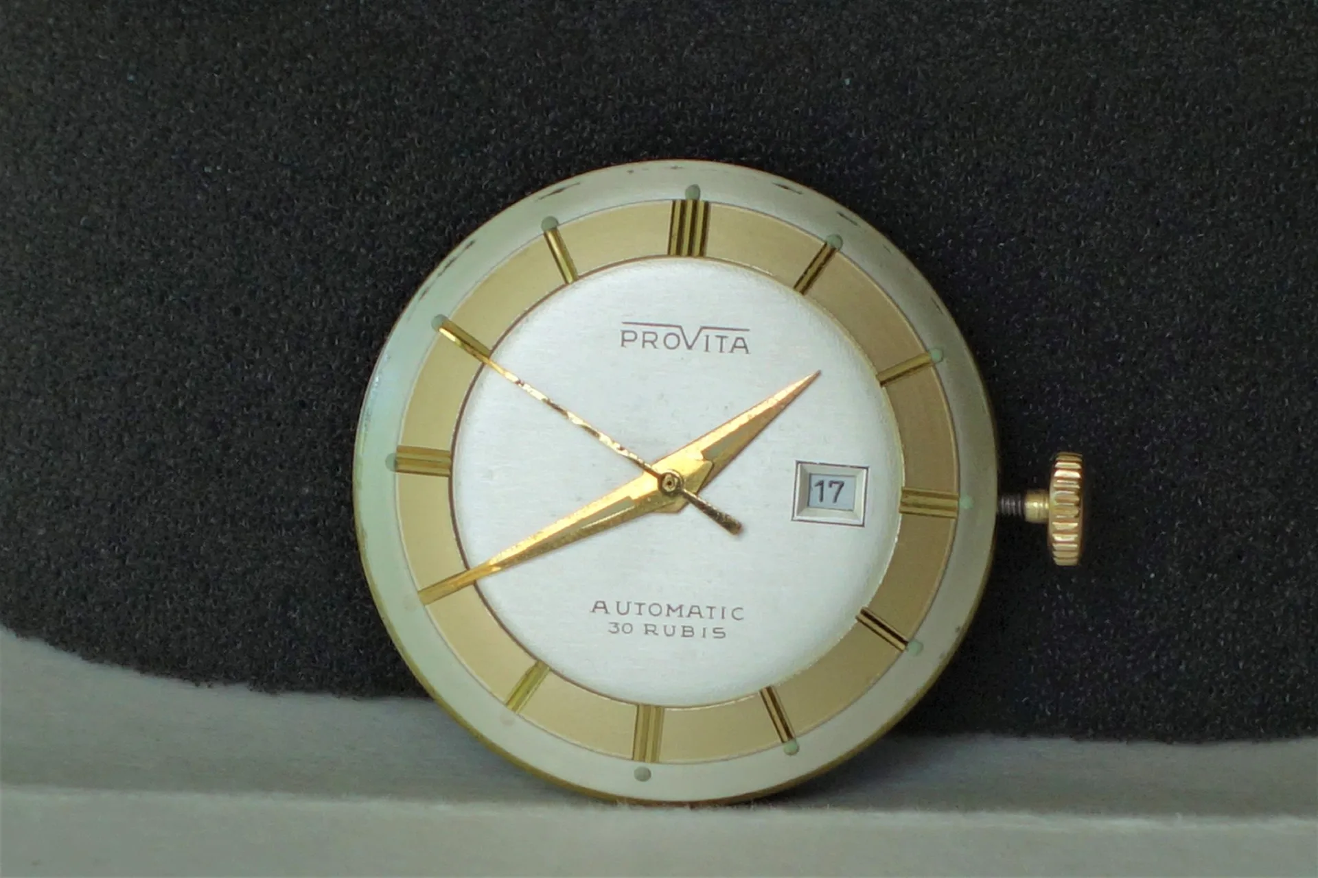 Automatik Uhrwerk mit Datum Rundes Automatik-Uhrwerk mit silberfarbenem und goldfarbenem Zifferblatt, goldfarbenen Zeigern und Datumsanzeige.