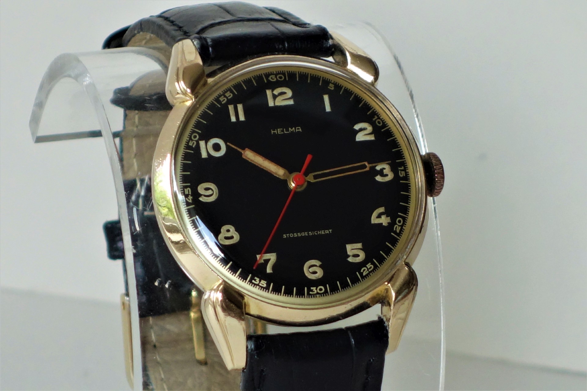 Schwarze Armbanduhr mit goldfarbenem Gehäuse und schwarzem Armband.