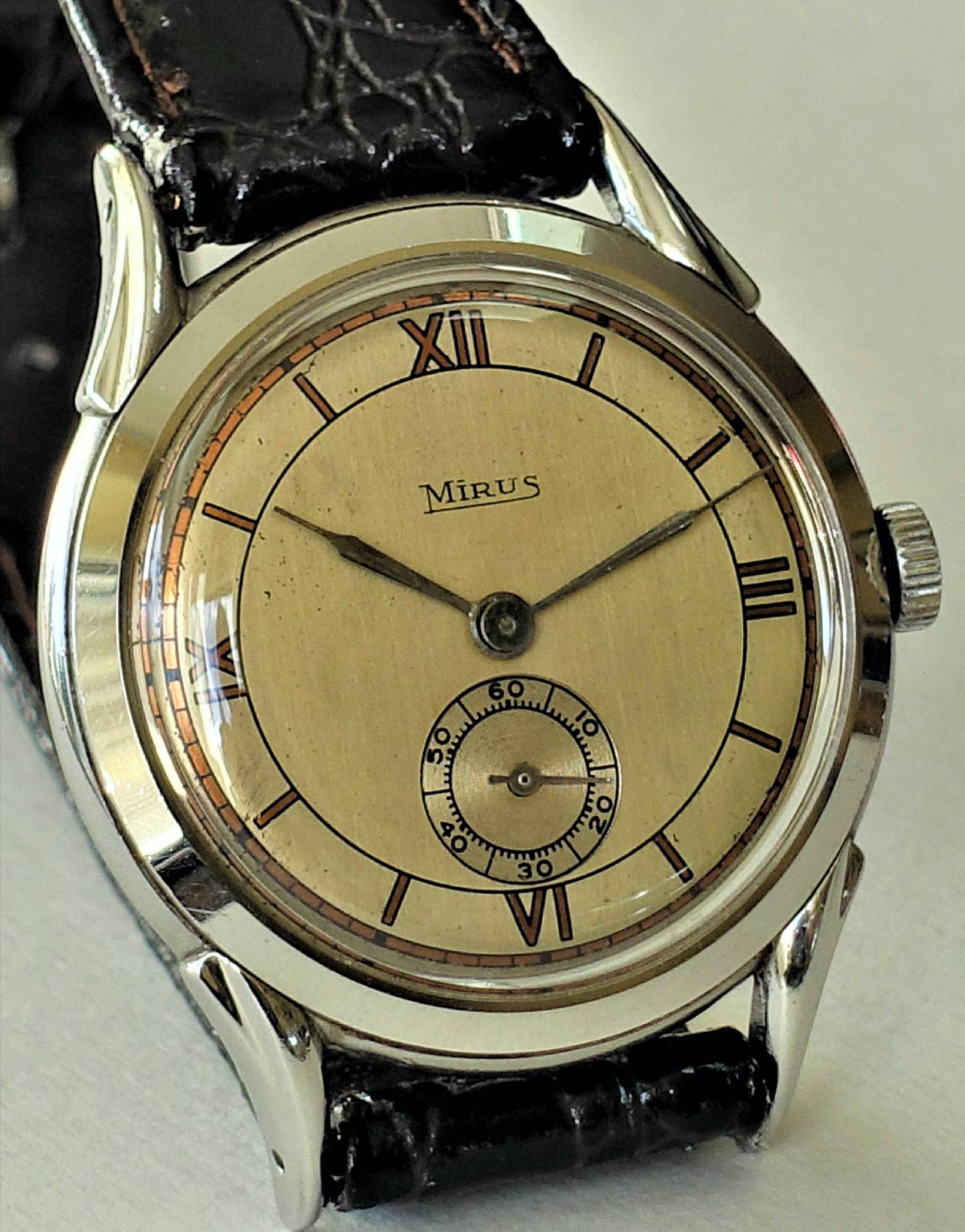 Eine klassische Armbanduhr mit cremefarbenem Zifferblatt, schwarzen Zeigern und schwarzem Armband.