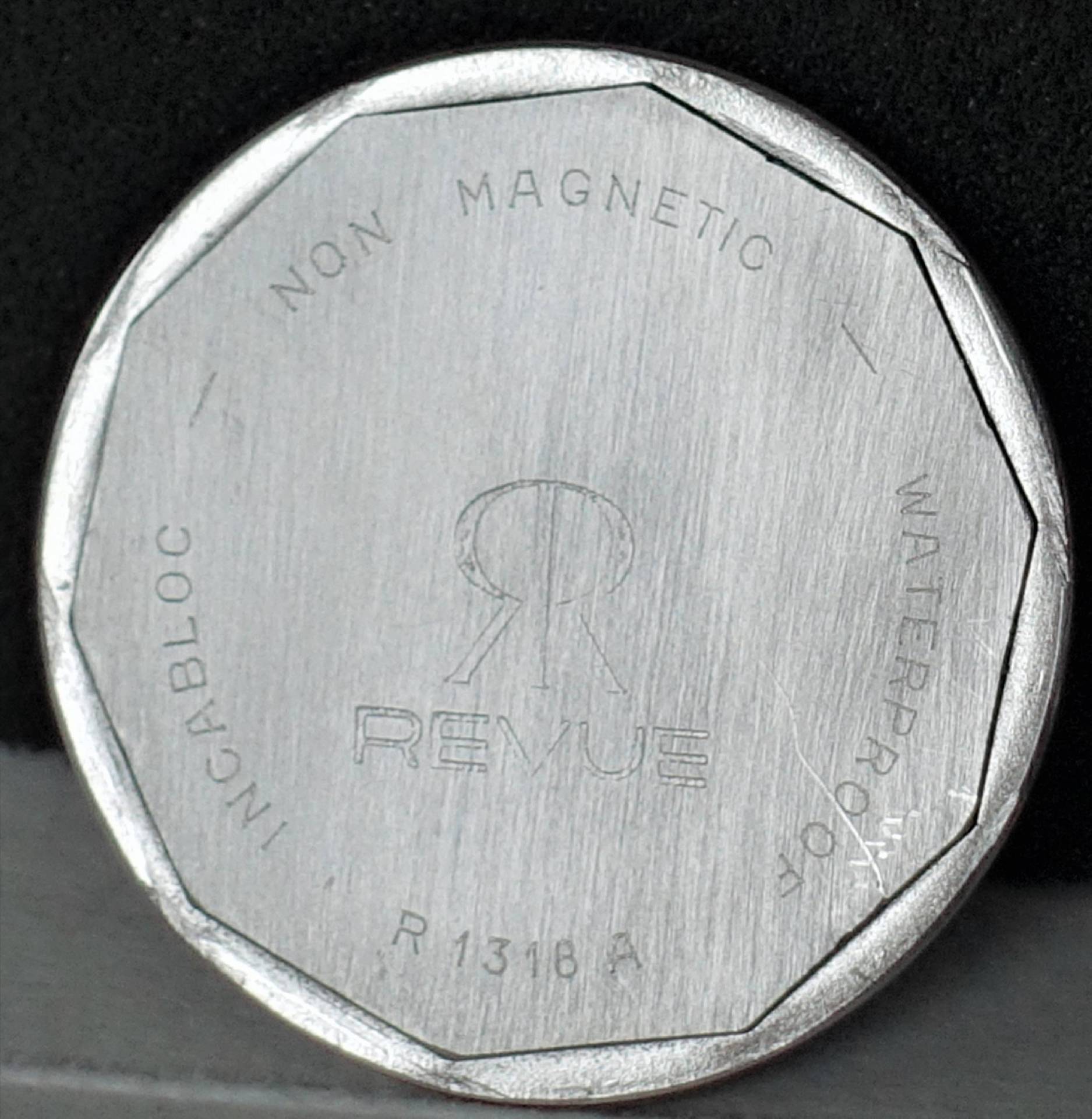 Silberfarbener Uhrenboden mit Revue-Logo und Gravur.