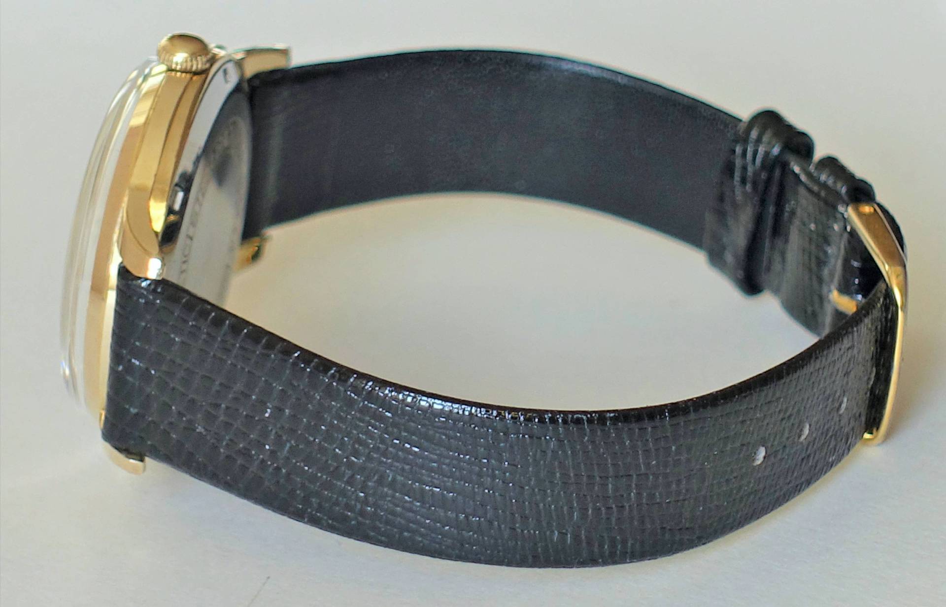Armbanduhr mit goldfarbenem Gehäuse und schwarzem Armband.