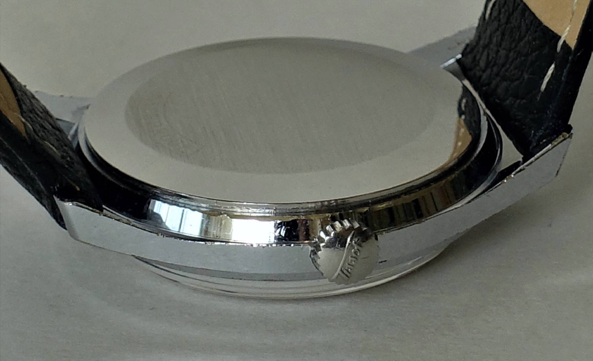 Silberfarbenes Uhrgehäuse mit schwarzem Armband und seitlicher Krone.