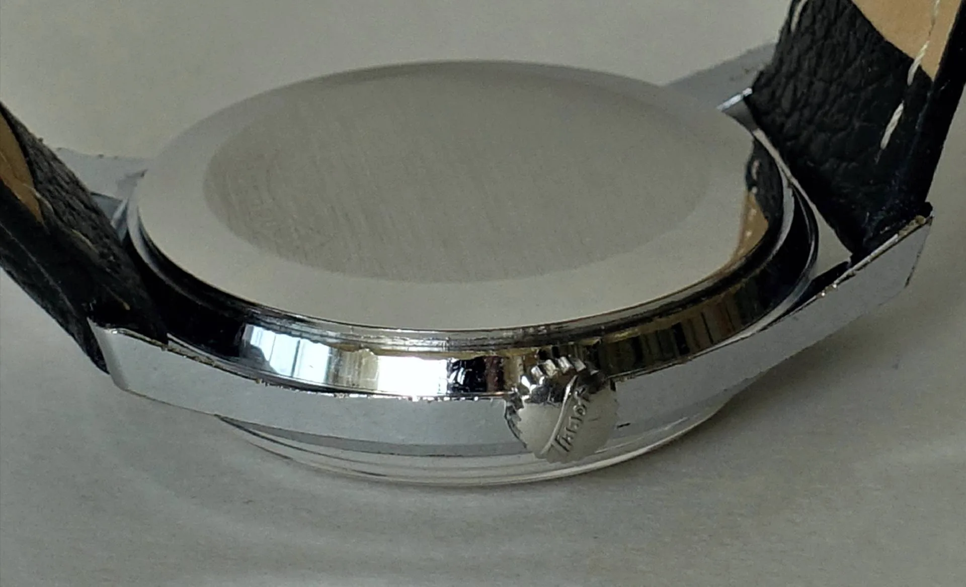 Silberfarbenes Uhrgehäuse mit schwarzem Armband und seitlicher Krone.