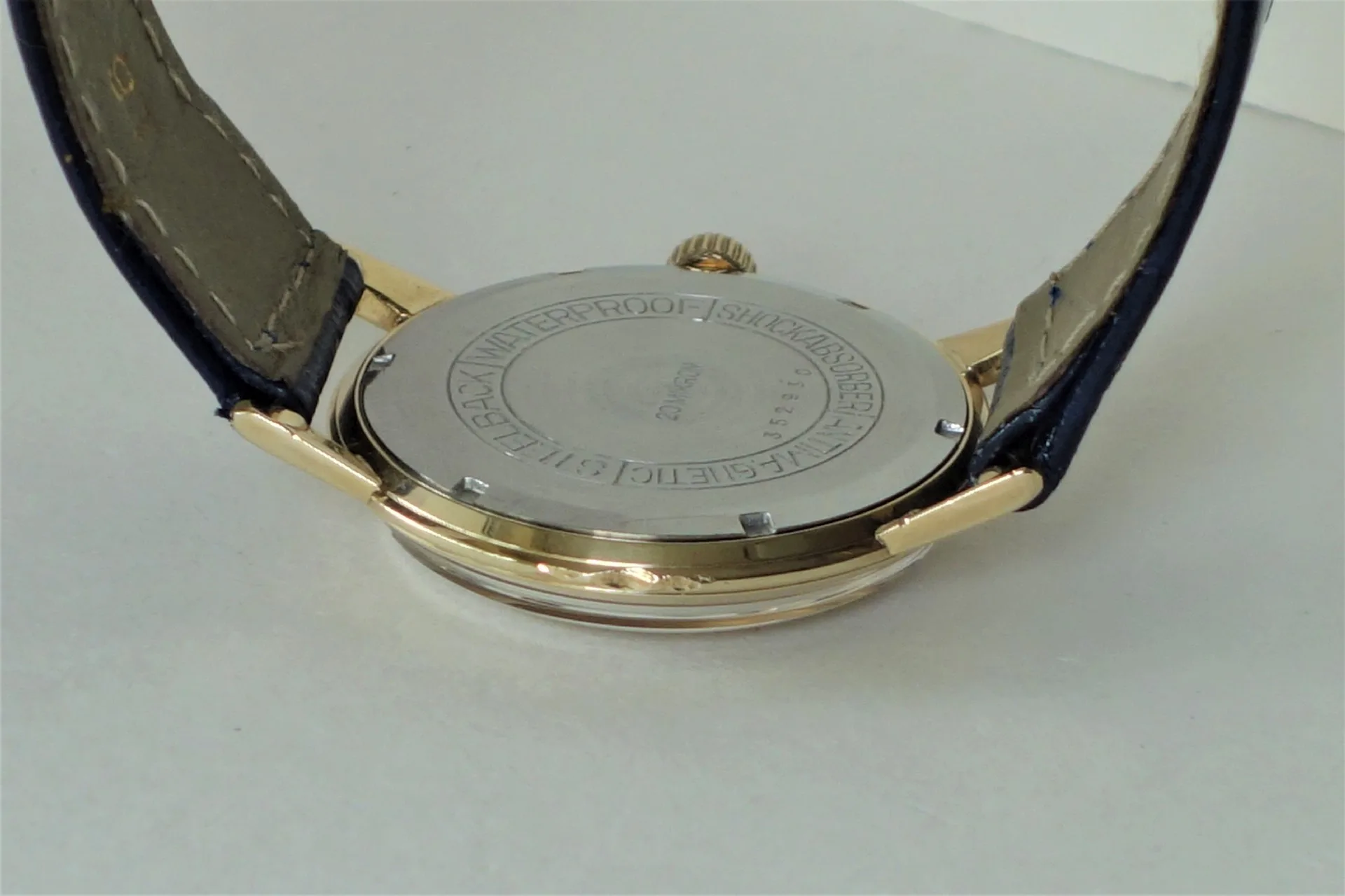 Uhrboden silberfarben Silberfarbener Uhrenboden mit Gravur an einer Armbanduhr mit dunklem Armband.