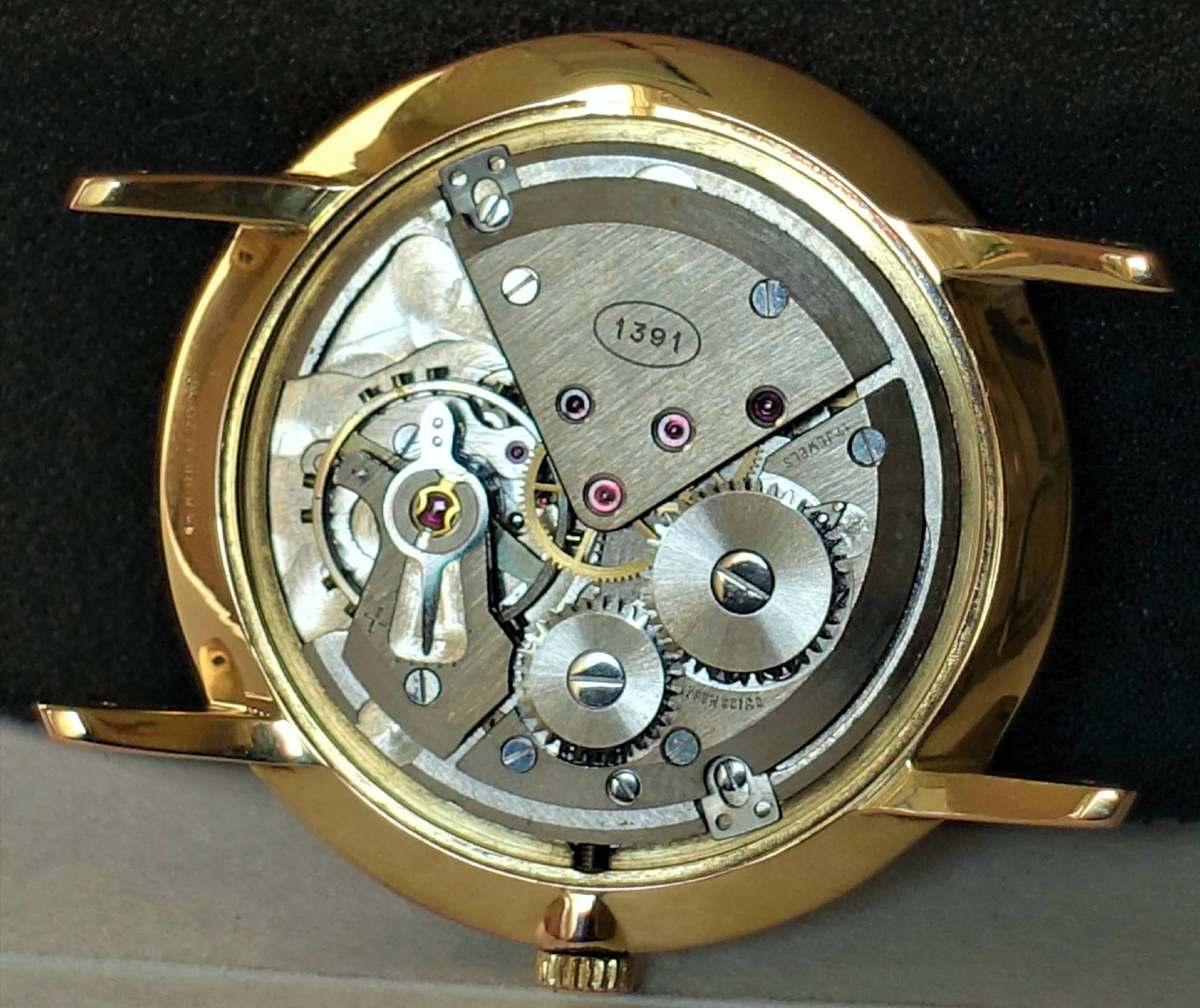 Mechanisches Uhrwerk im Gehäuse Mechanisches Uhrwerk in einem goldfarbenen Uhrengehäuse ohne Zifferblatt und Zeiger.