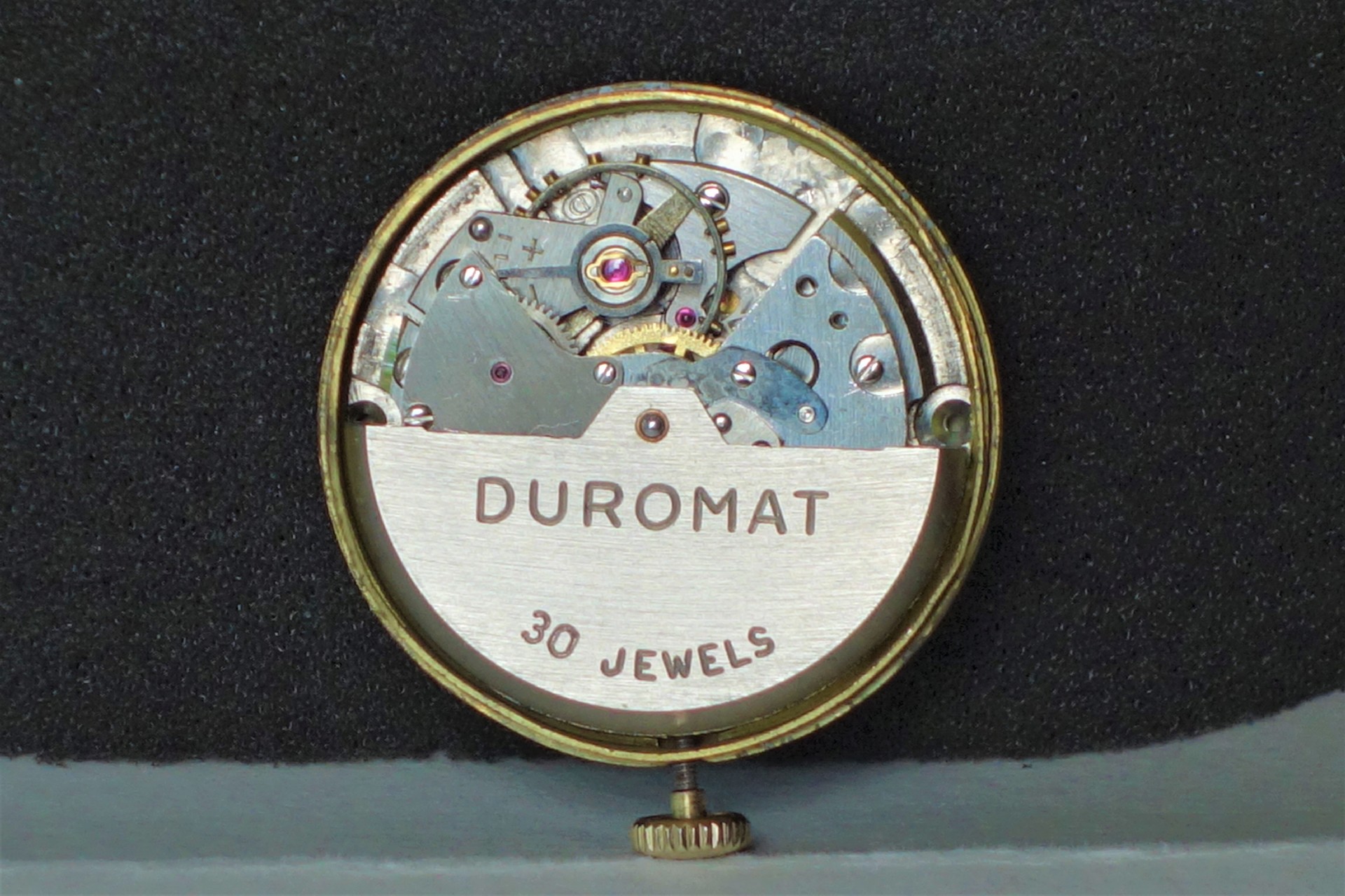 Mechanisches Uhrwerk mit der Aufschrift "Duromat 30 Jewels" in silberner Farbe.