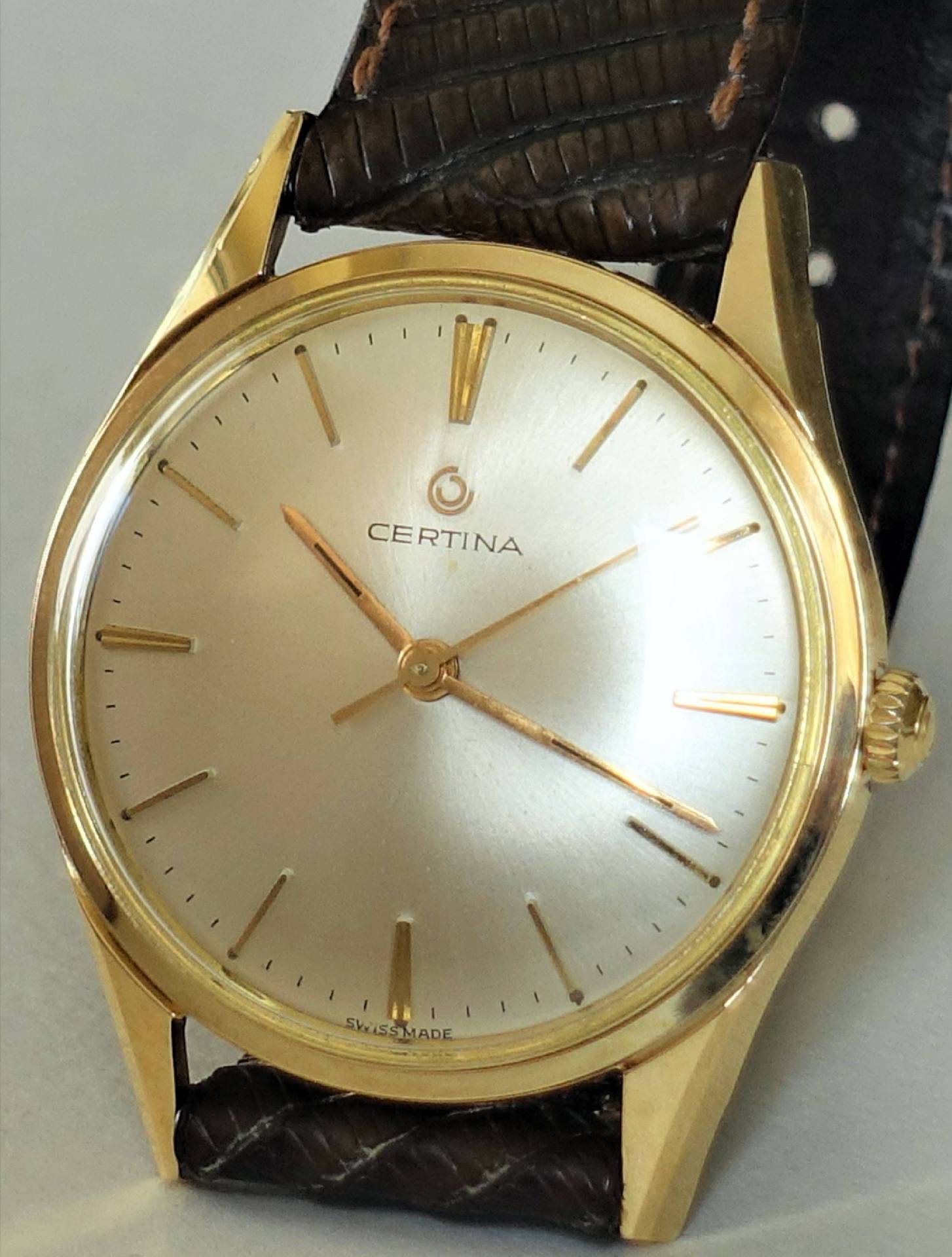 Goldfarbene Certina Armbanduhr mit hellem Zifferblatt und braunem Lederarmband.