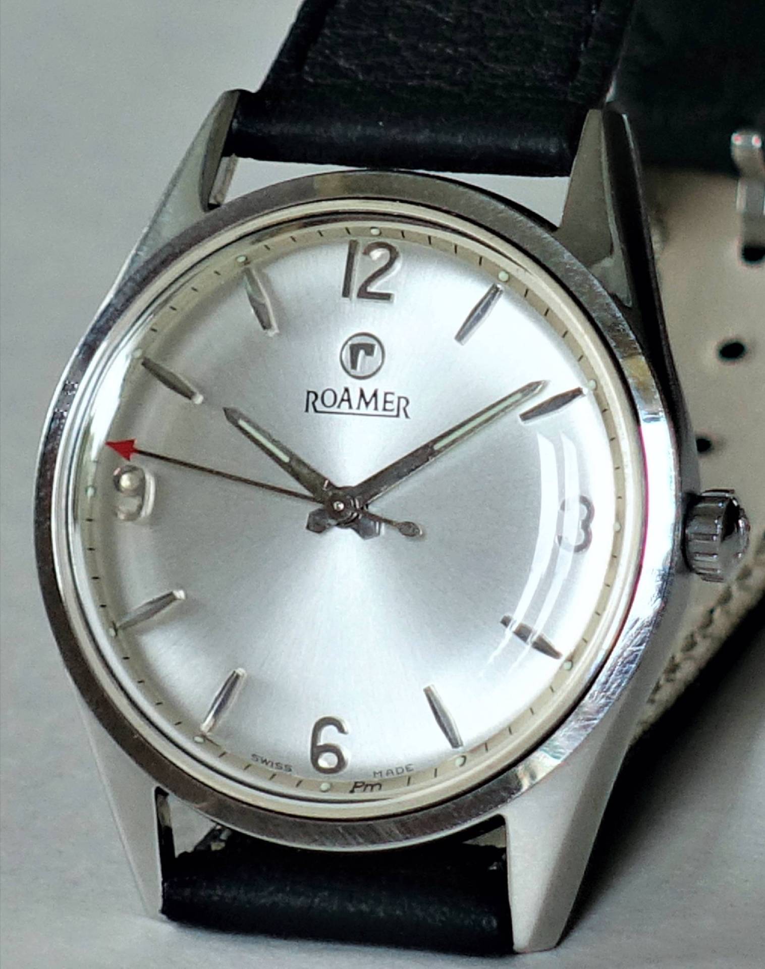 Silberfarbene Armbanduhr mit schwarzem Lederarmband und schlichtem Zifferblatt.