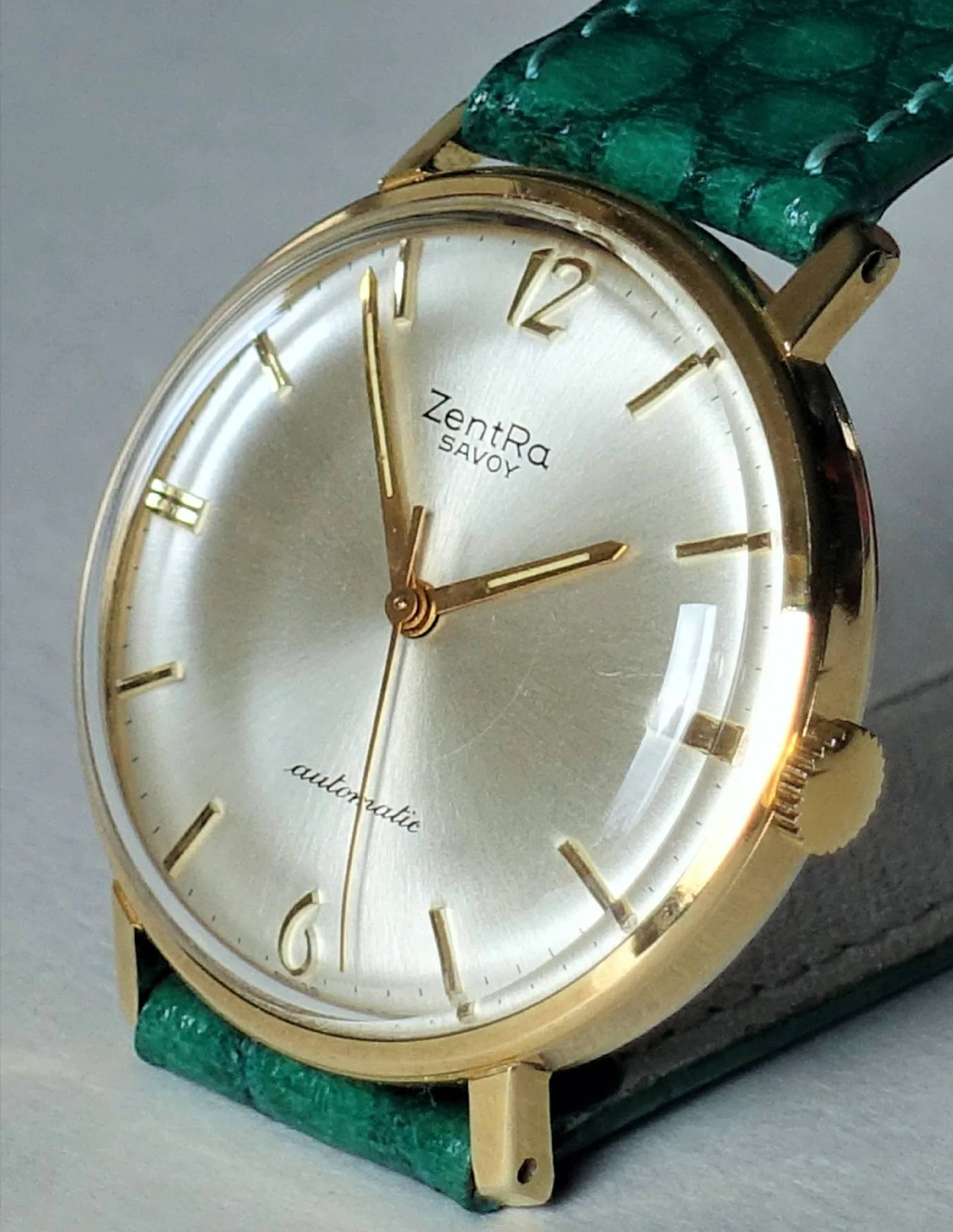 Armbanduhr goldfarben Goldfarbene Armbanduhr mit hellem Zifferblatt und grünem Armband.