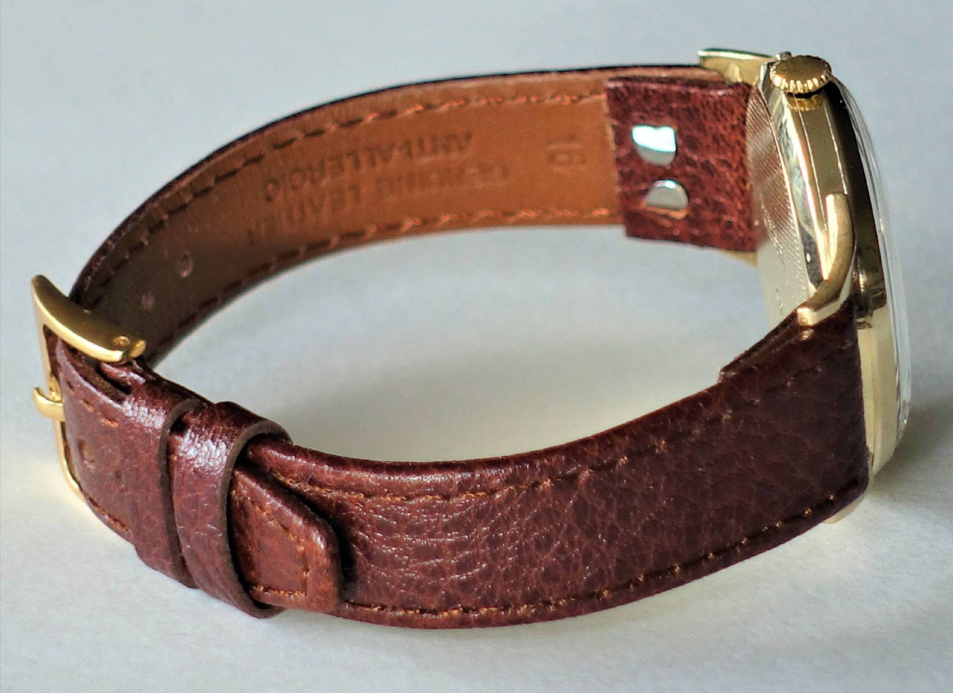 Armbanduhr mit braunem Armband und goldfarbenem Gehäuse.