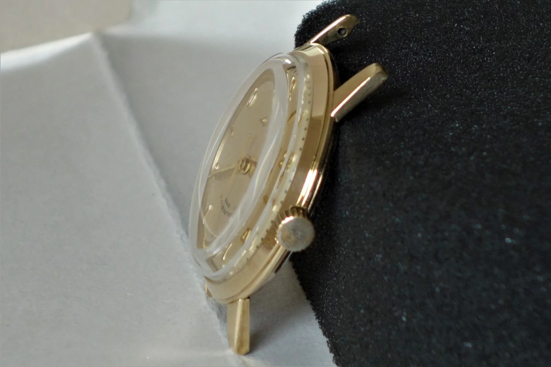 Goldfarbenes Uhrgehäuse mit Krone und montiertem Zifferblatt ohne Armband.
