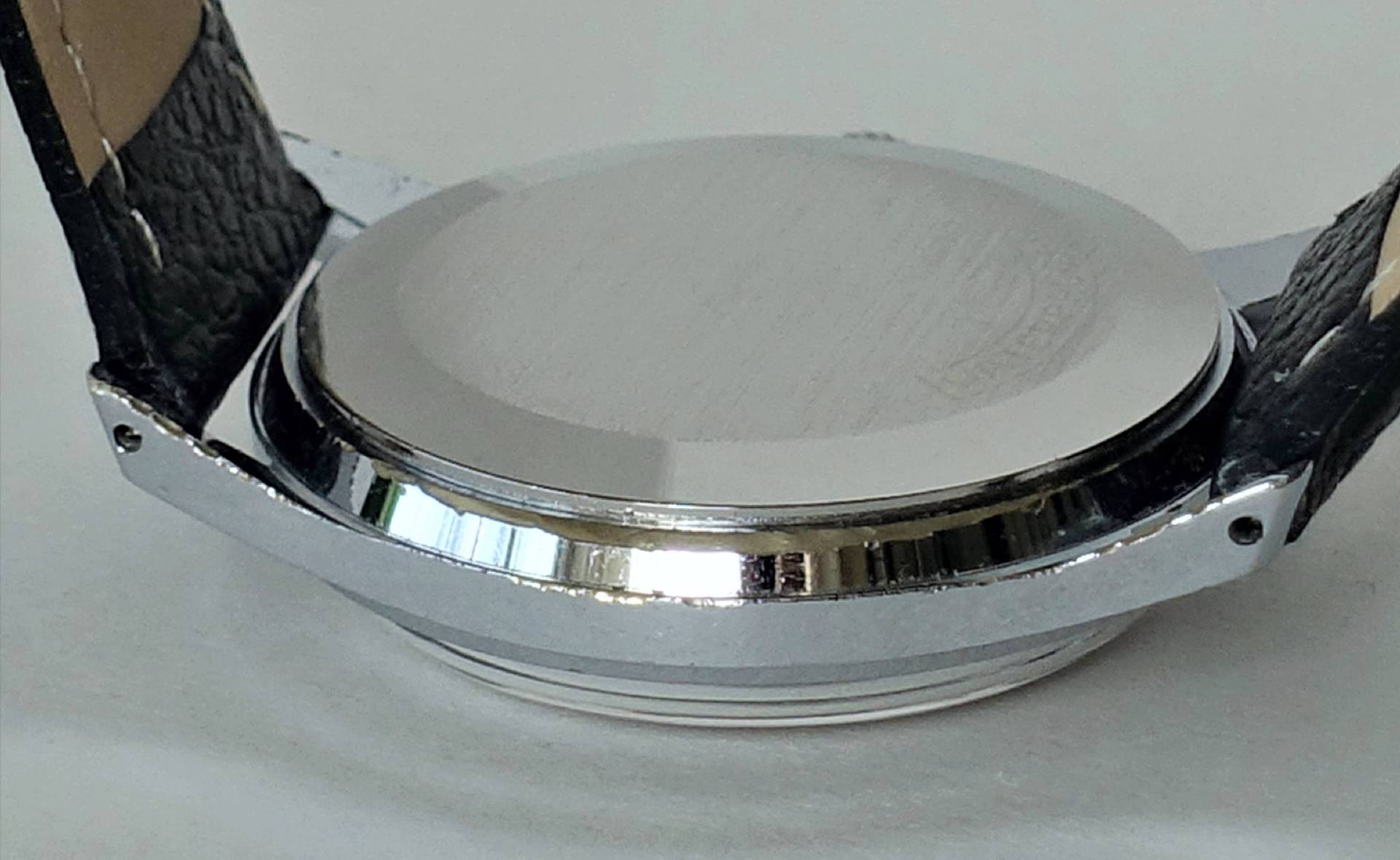 Rückseite einer silberfarbenen Armbanduhr mit schwarzem Armband.