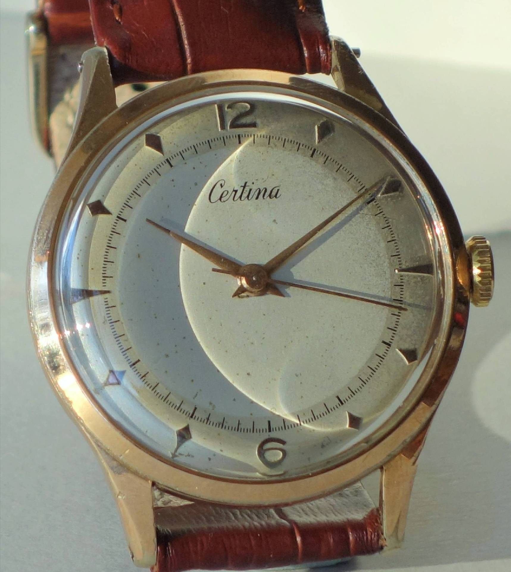Goldfarbene Certina Armbanduhr mit hellem Zifferblatt und braunem Armband.