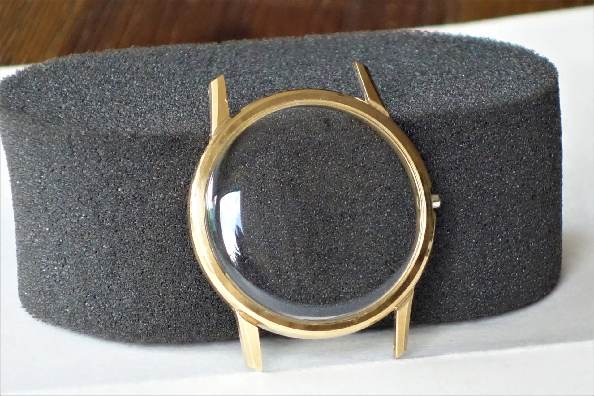 Rundes Uhrengehäuse in goldfarbener Optik mit gewölbtem Glas.