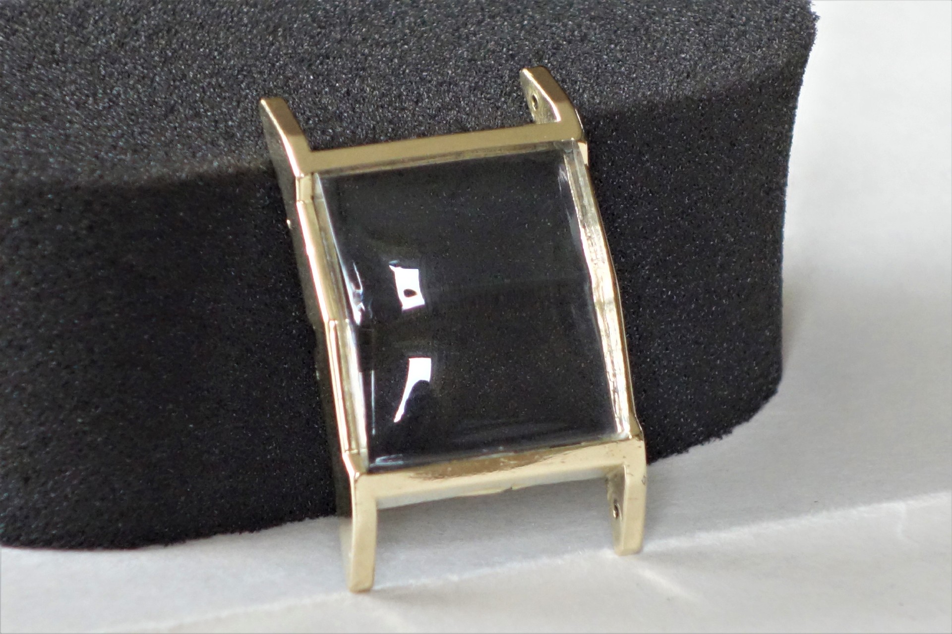 Rechteckiges Uhrengehäuse in goldfarbener Ausführung mit gewölbtem Glas.