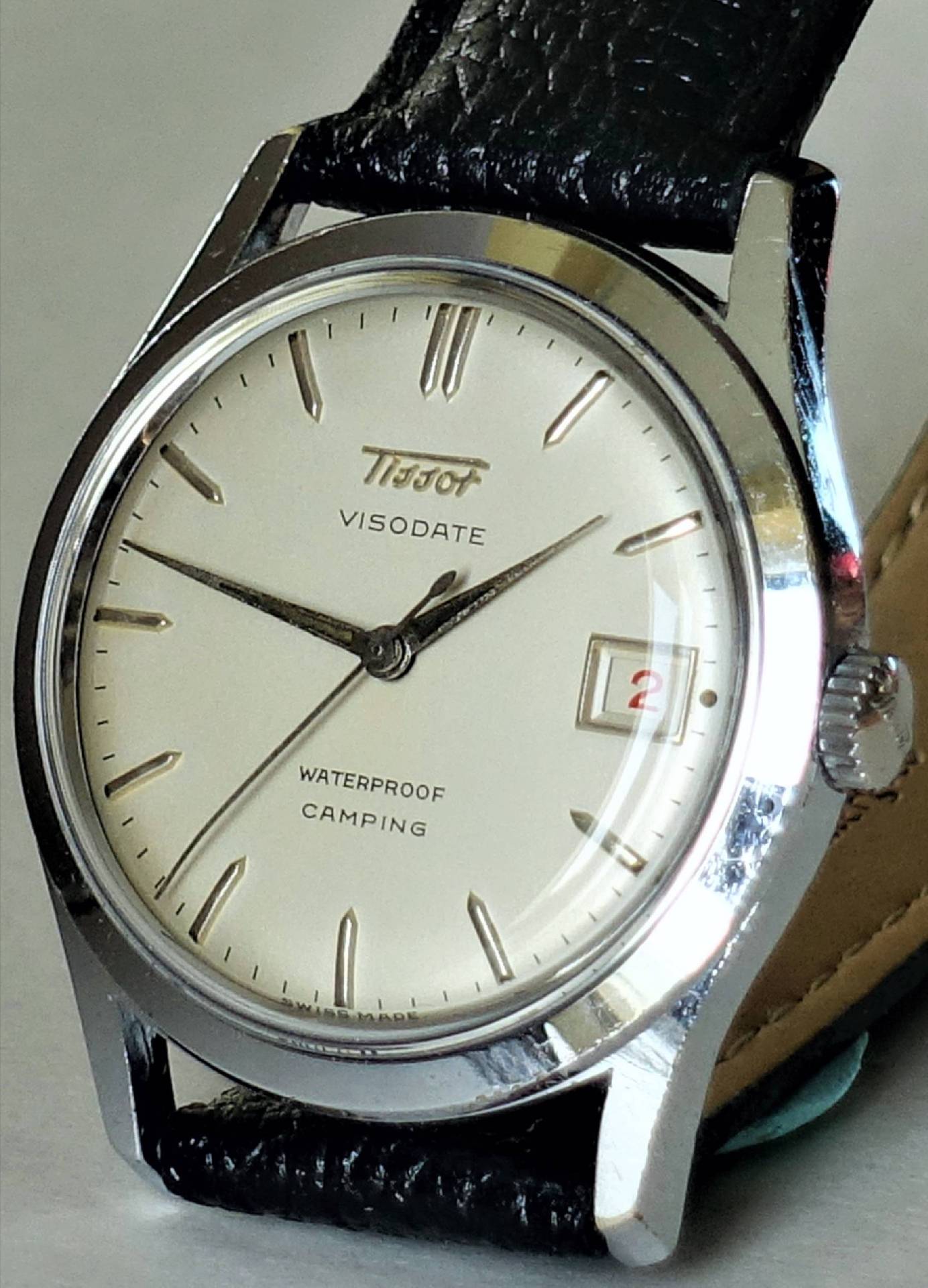 Silberfarbene Armbanduhr mit hellem Zifferblatt, schwarzem Lederarmband und Datumsanzeige.