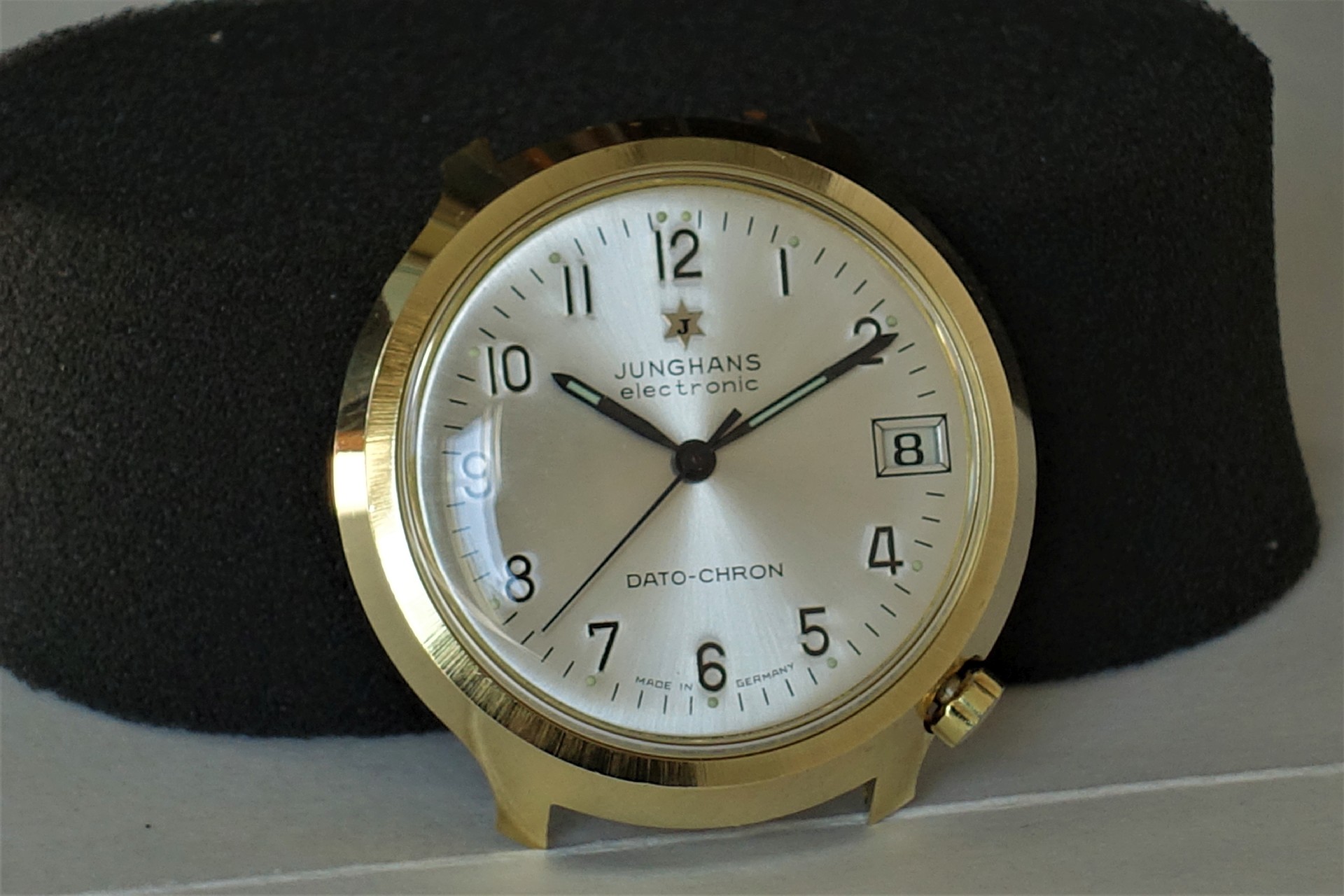 Runde Armbanduhr mit hellem Zifferblatt, schwarzer Beschriftung und goldfarbenem Gehäuse.