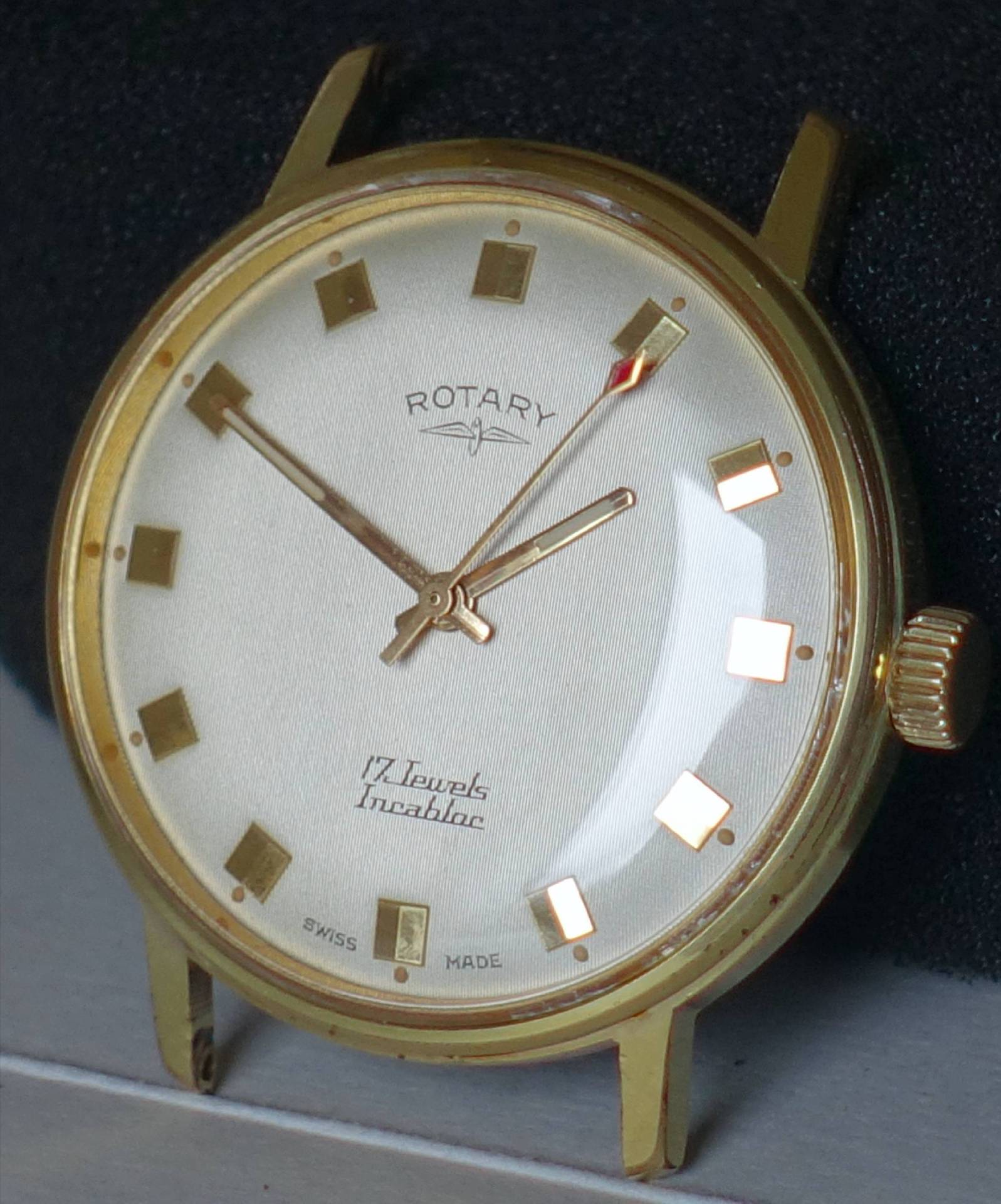 Goldfarbene Armbanduhr mit hellem Zifferblatt und eckigen Stundenmarkierungen.