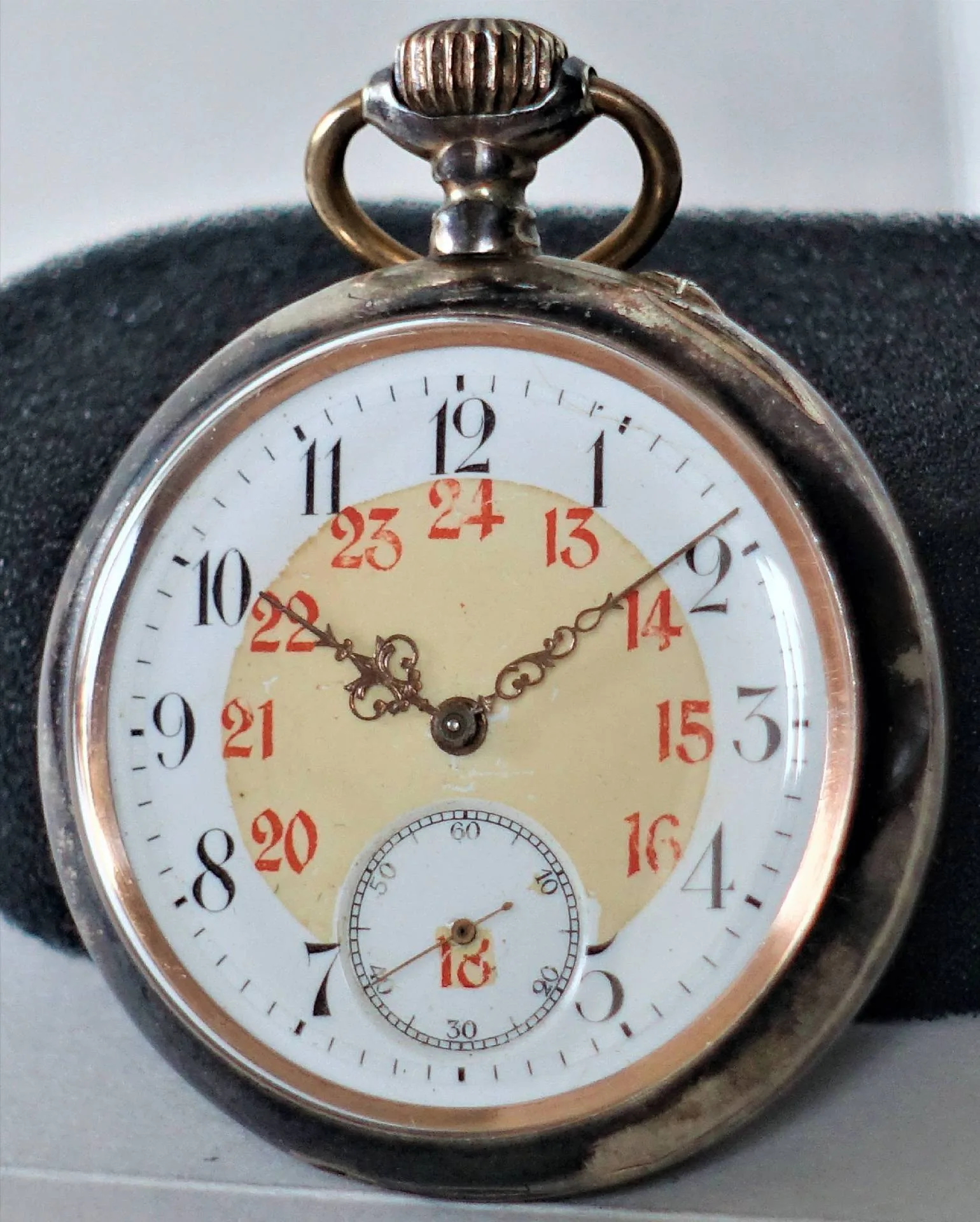 Taschenuhr silberfarben Runde silberfarbene Taschenuhr mit weißem Zifferblatt, schwarzen und roten Zahlen sowie verzierten Zeigern.