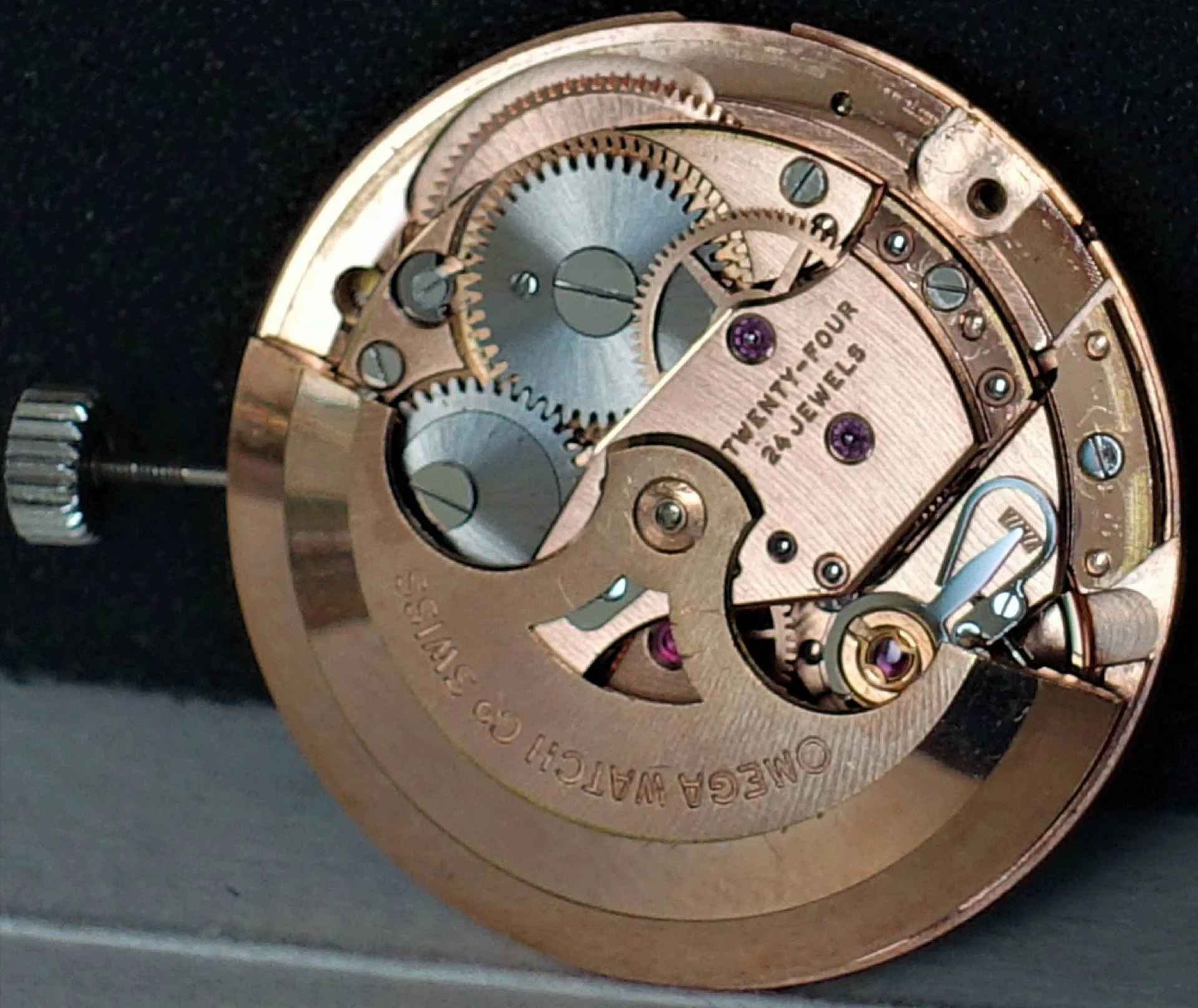 Mechanisches Automatik-Uhrwerk von Omega in goldfarbener Ausführung mit sichtbaren Zahnrädern und Aufzugswelle.