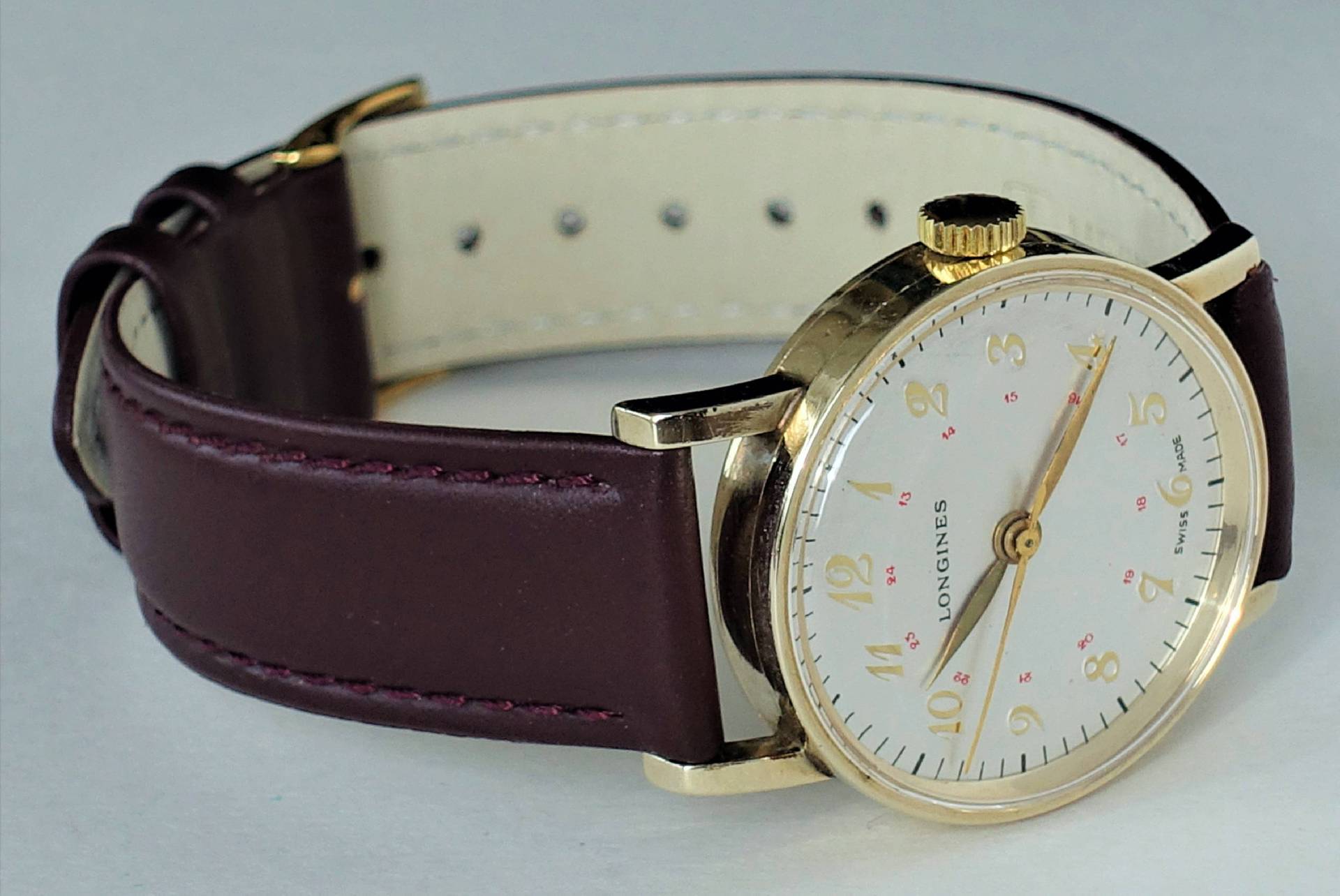 Longines Armbanduhr mit goldfarbenem Zifferblatt und braunem Lederarmband