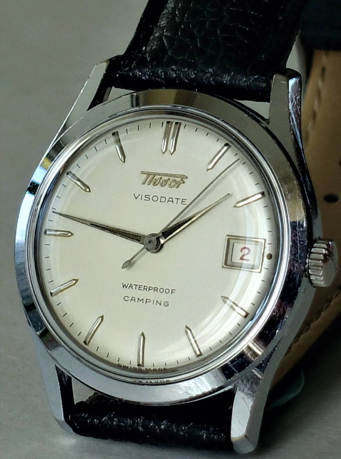 Tissot Visodate Armbanduhr Silberfarbene Armbanduhr mit hellem Zifferblatt, schwarzem Lederarmband und Datumsanzeige.