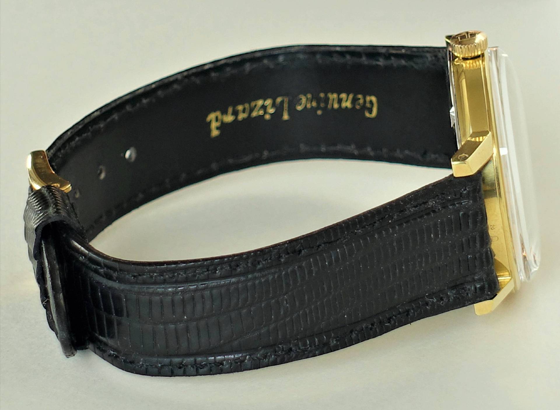 Schwarze Armbanduhr mit goldfarbenem Gehäuse und schwarzem Lederarmband.
