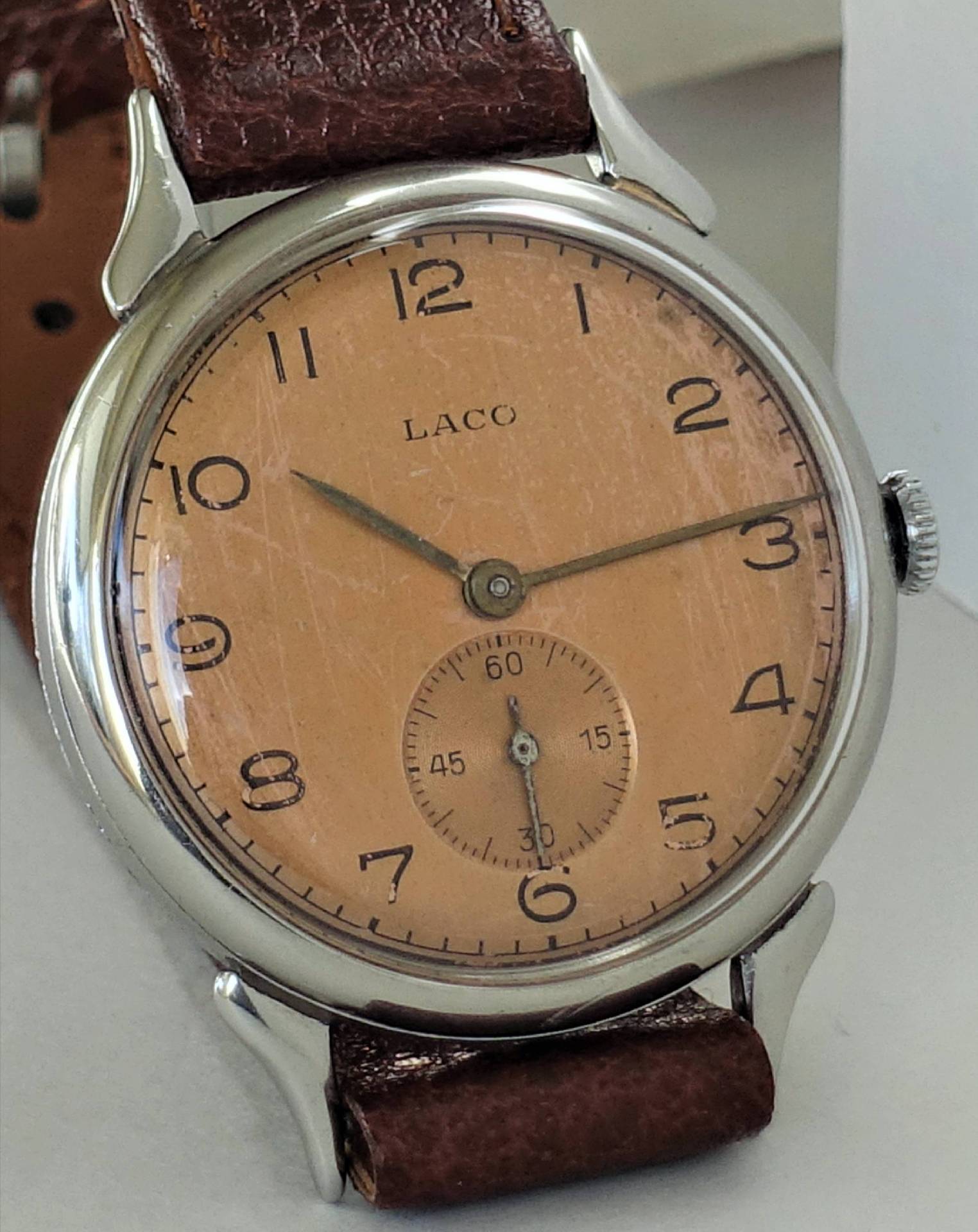 Vintage Armbanduhr mit beigem Zifferblatt, braunem Armband und silberfarbenem Gehäuse.