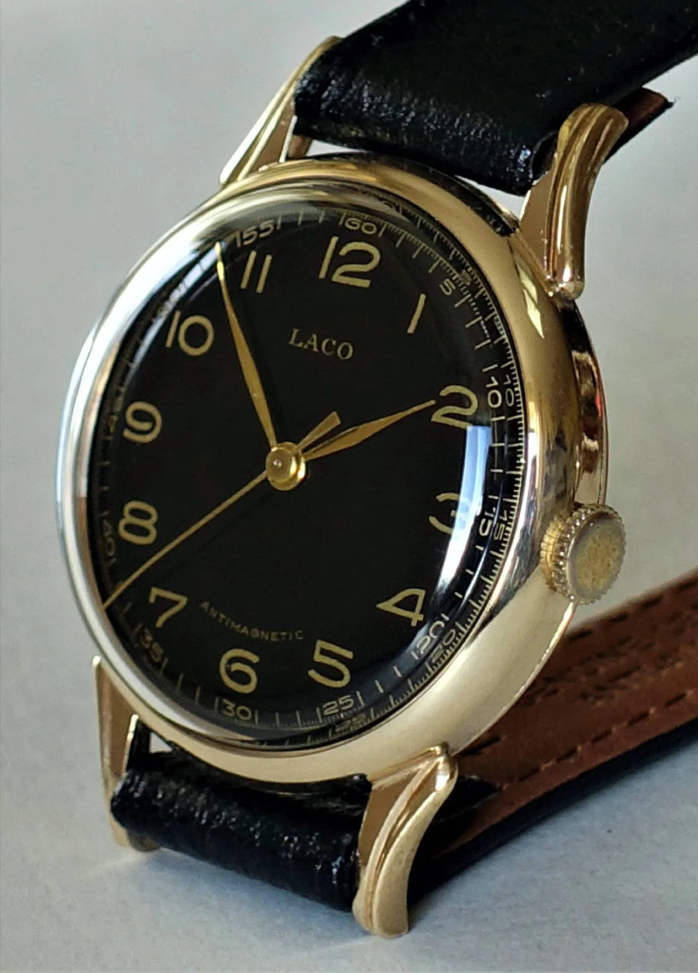 Schwarzes Zifferblatt, goldenes Gehäuse Eine Armbanduhr mit schwarzem Zifferblatt, goldfarbenem Gehäuse und goldenen Zeigern sowie schwarzem Lederarmband.