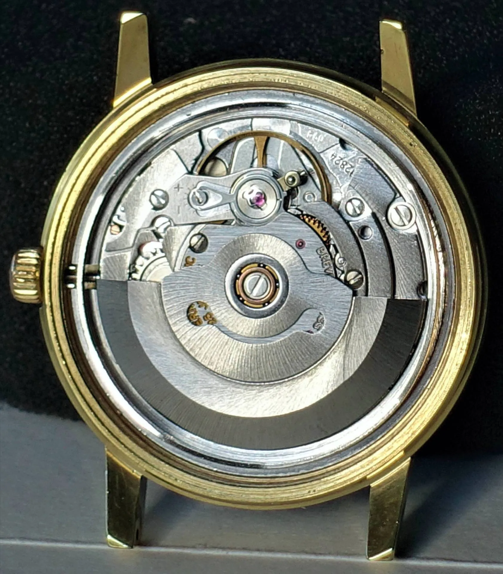 Automatik Uhrwerk im Gehäuse Silberfarbenes Automatik-Uhrwerk in einem goldfarbenen Uhrengehäuse ohne Rückdeckel.