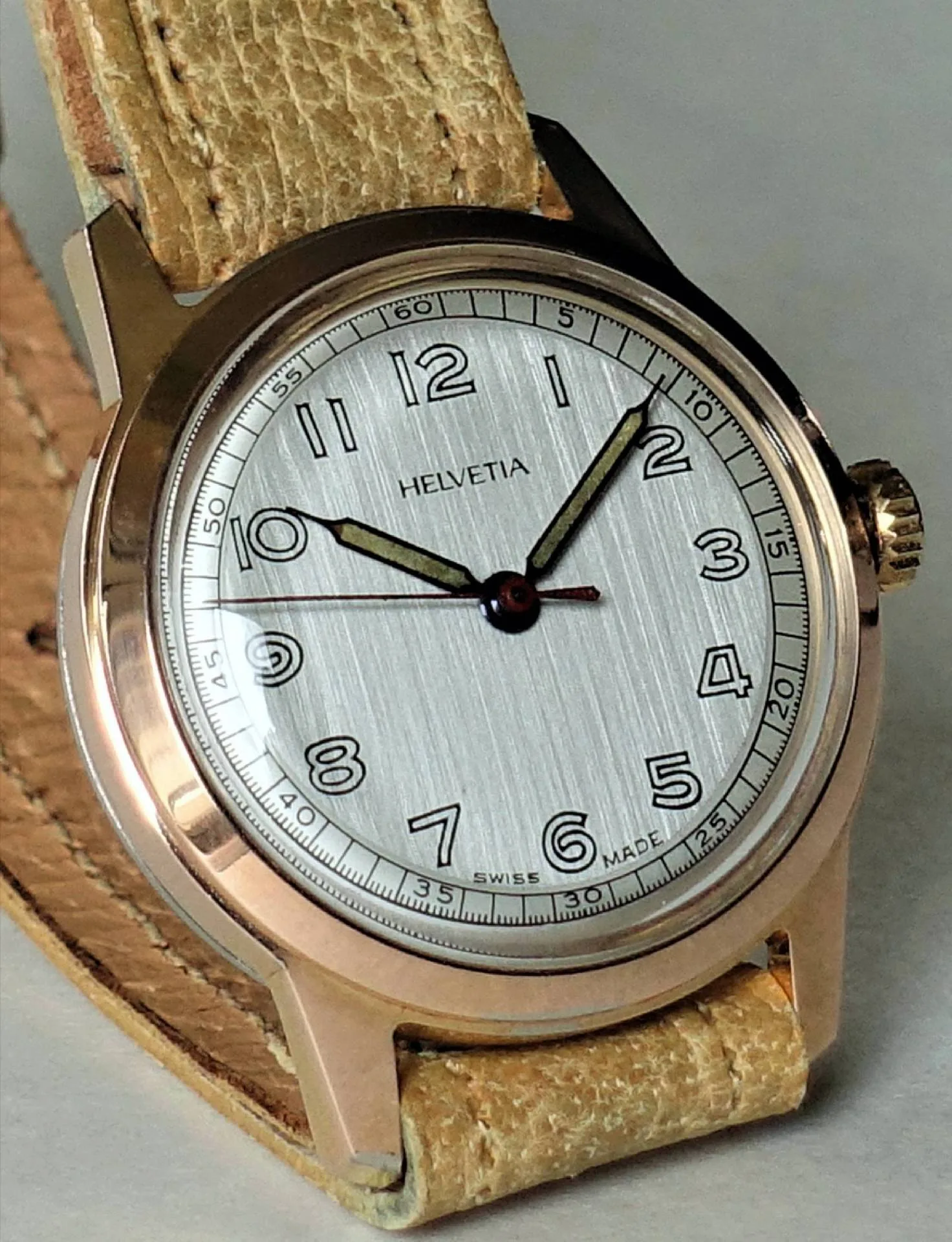 Helvetia Armbanduhr silberfarben Silberfarbene Armbanduhr mit hellem Zifferblatt, schwarzen Zahlen und beigem Lederarmband.